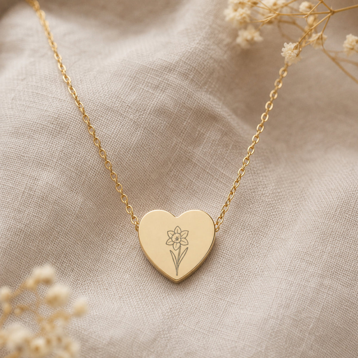 March birth flower necklace with daffodil engraving on linen flatlay with full chain