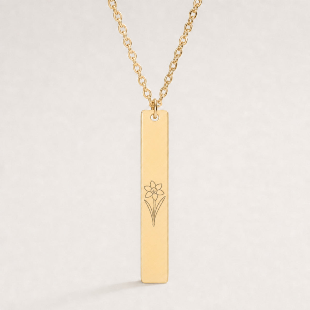 December birth flower necklace — Narcissus engraved on 1.26" × 0.20" vertical bar pendant, premium close-up macro hero on 18K Gold PVD