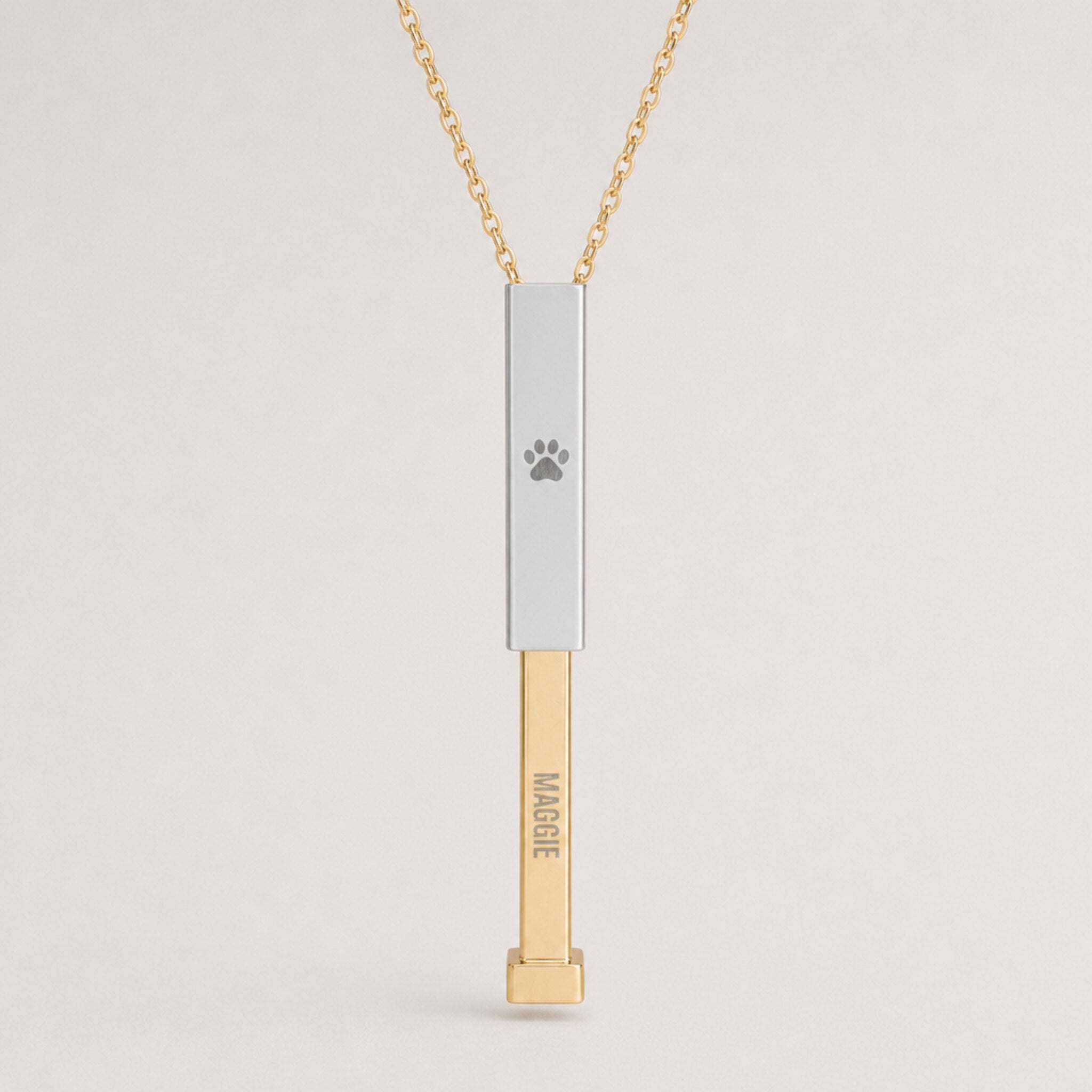 Close-up of the dog paw cutout sliding bar pendant in gold and stainless steel, engraved hidden-message necklace