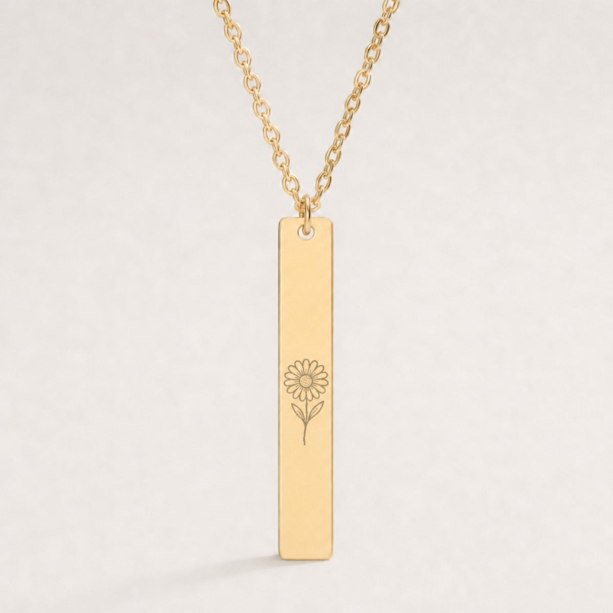 April birth flower necklace — Daisy engraved on 1.26" × 0.20" vertical bar pendant, premium close-up macro hero on 18K Gold PVD polished mirror, premium 316L stainless steel