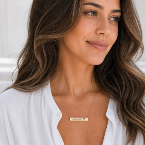 Aquarius zodiac necklace — engraved cutout heart bar pendant, 18K Gold PVD finish, model wearing pendant, on-neck lifestyle