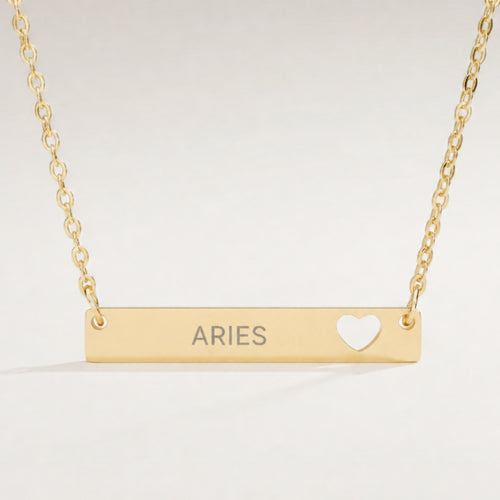 Aries zodiac necklace — engraved horizontal cutout heart bar pendant, premium close-up macro hero, 18K Gold PVD polished mirror, grey laser-etched ARIES, see-through heart cutout, 316L stainless steel
