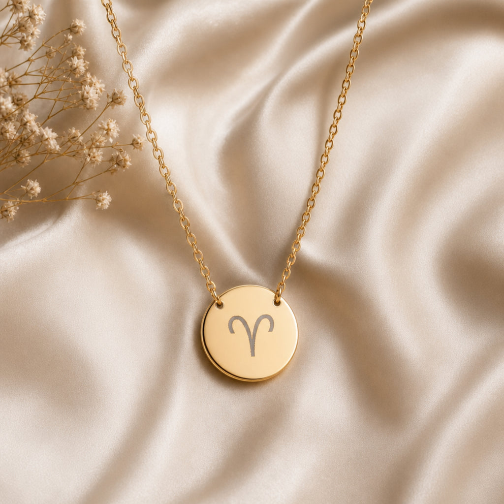 Aries zodiac coin necklace flatlay — 18K gold pendant on cream silk with dried baby's breath, laser-engraved Aries star sign