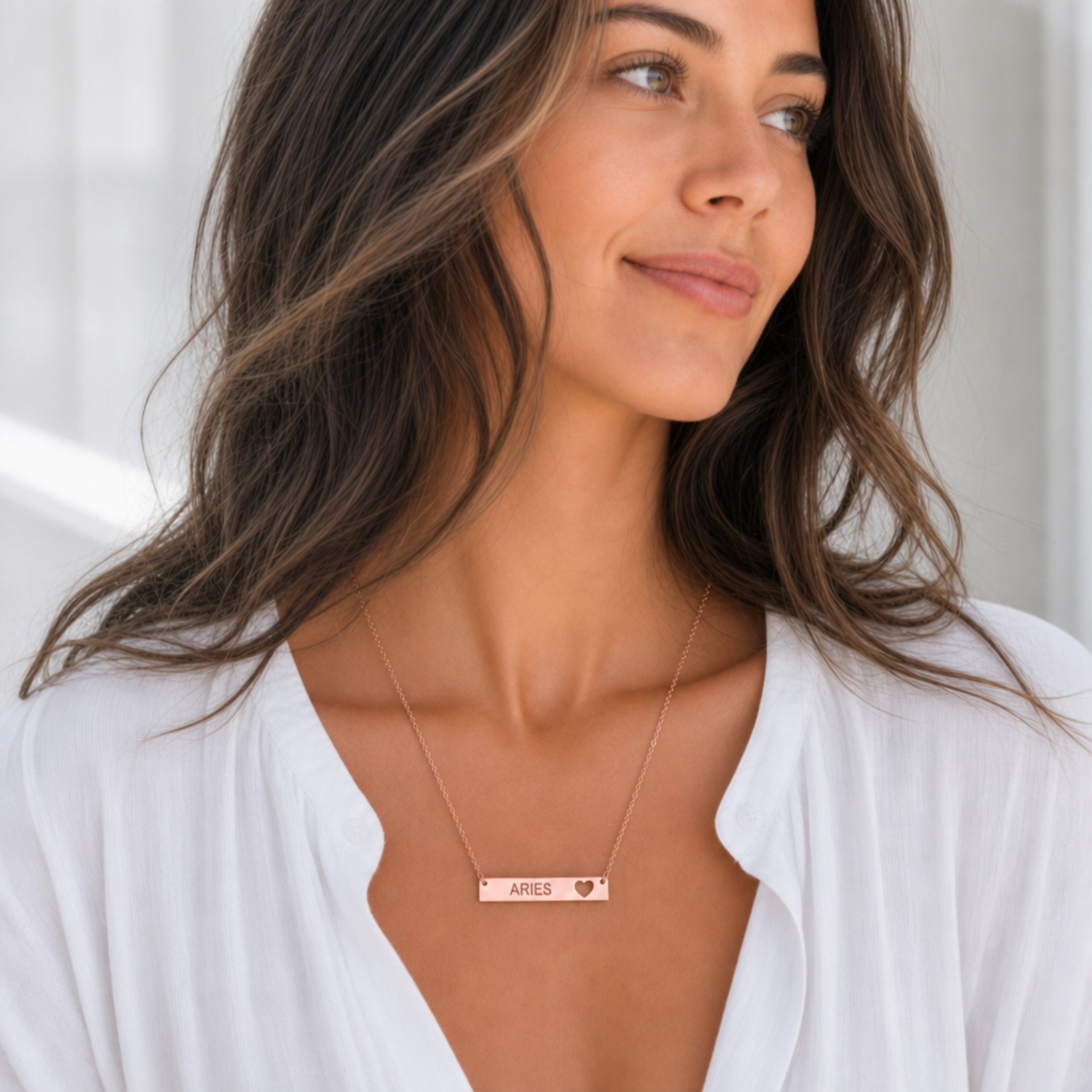 Aries zodiac necklace — engraved cutout heart bar pendant, 18K Rose Gold PVD finish, model wearing pendant on white blouse, on-neck lifestyle, bright editorial daylight