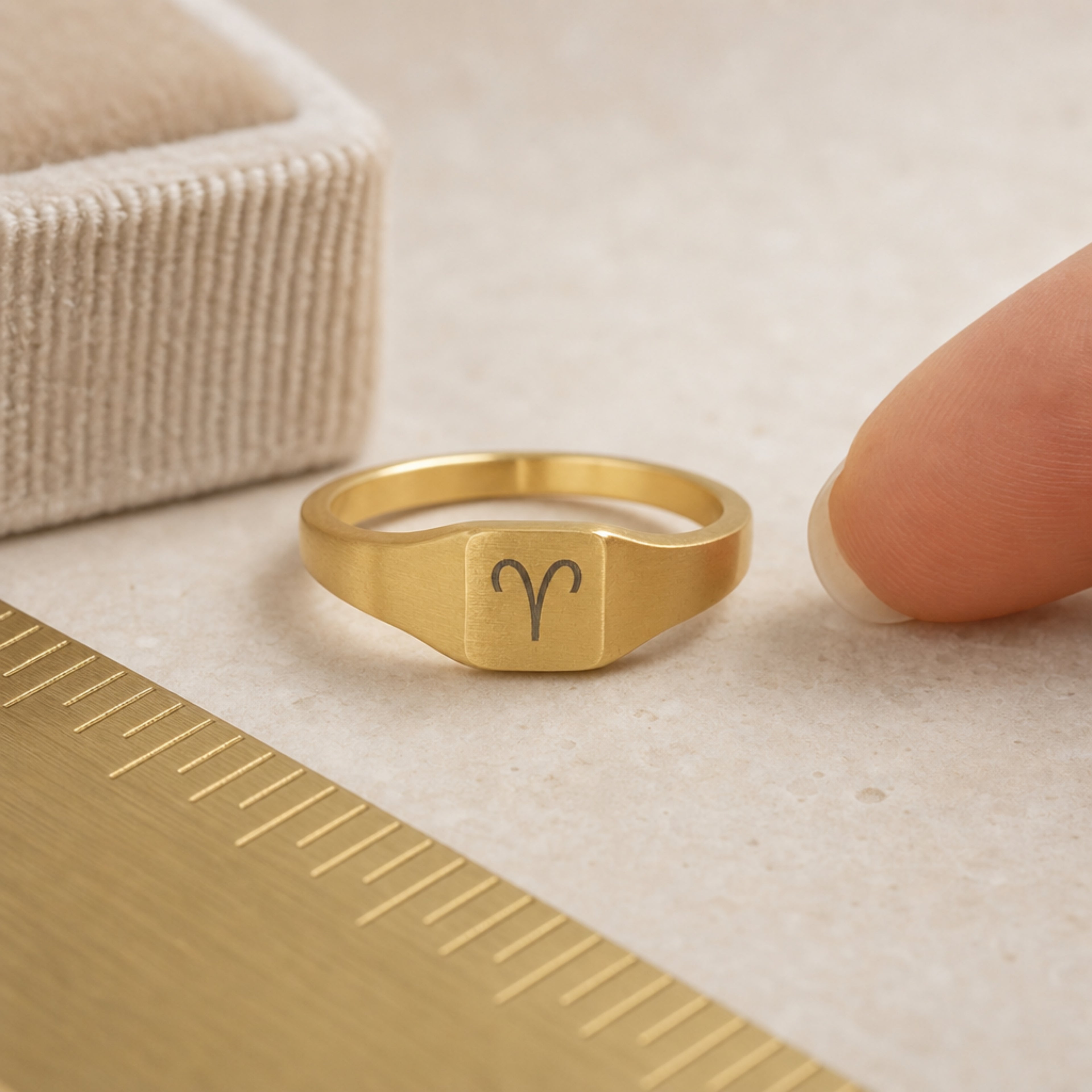 Aries zodiac square signet ring scale-in-hand — fingers holding ring next to gift box and ruler, dainty 20mm signet sizing