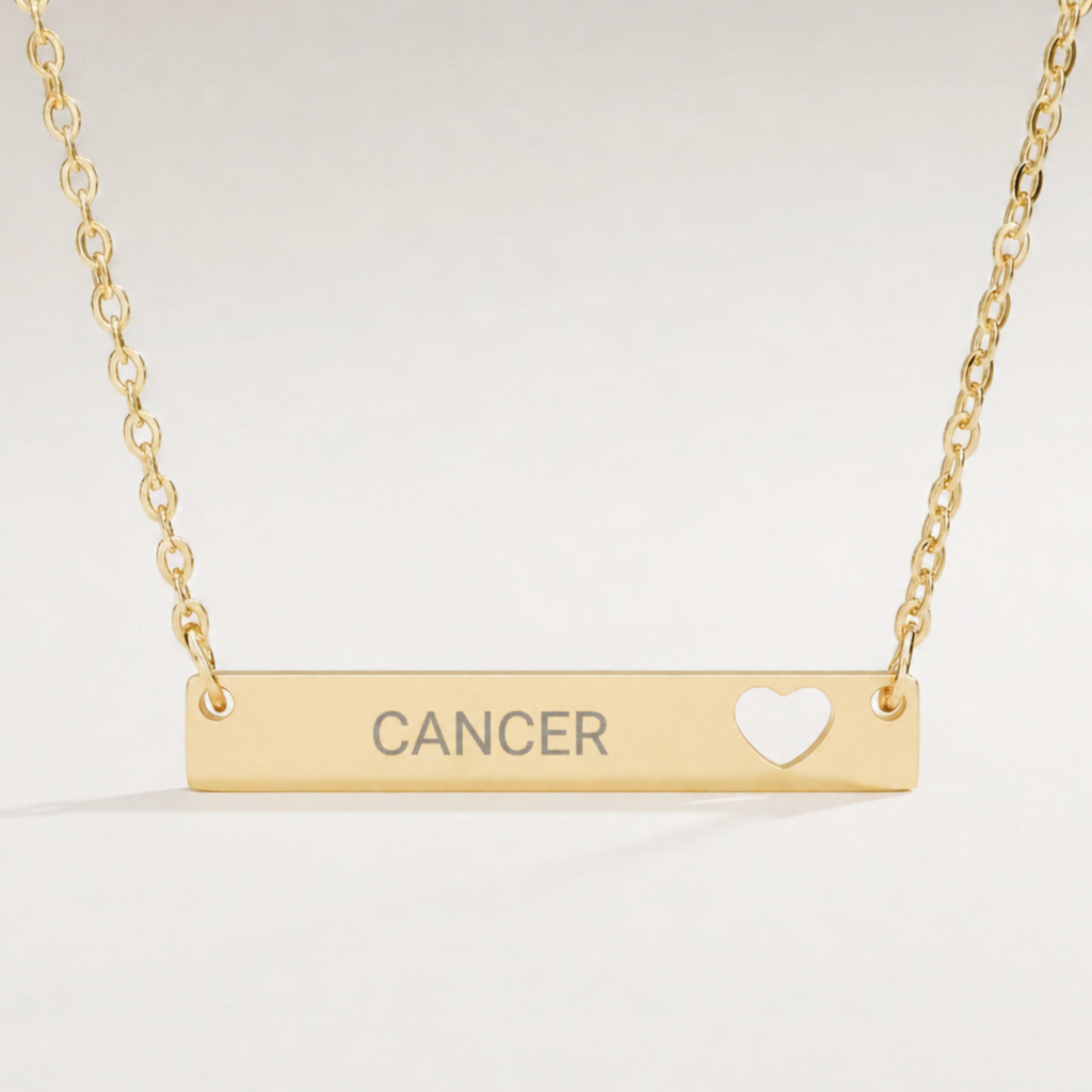 Cancer zodiac necklace close-up — 18K Gold polished cutout heart bar pendant with grey laser-etched CANCER, see-through heart cutout, premium macro on clean background