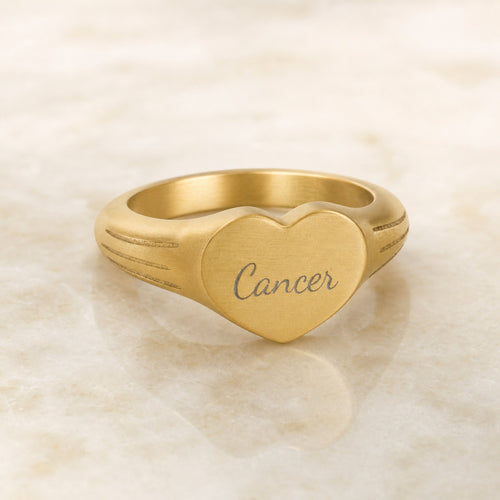 Cancer zodiac heart signet ring — hero macro of laser-engraved Cancer name in Dancing Script cursive on 18K gold heart face