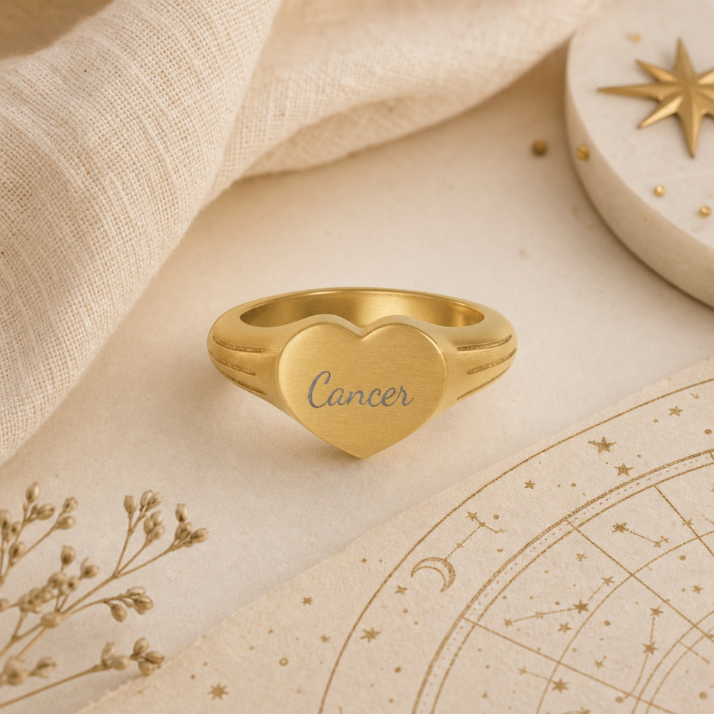Cancer zodiac heart signet ring celestial flatlay — zodiac chart and brass star with engraved Cancer heart signet, astrology gift styling