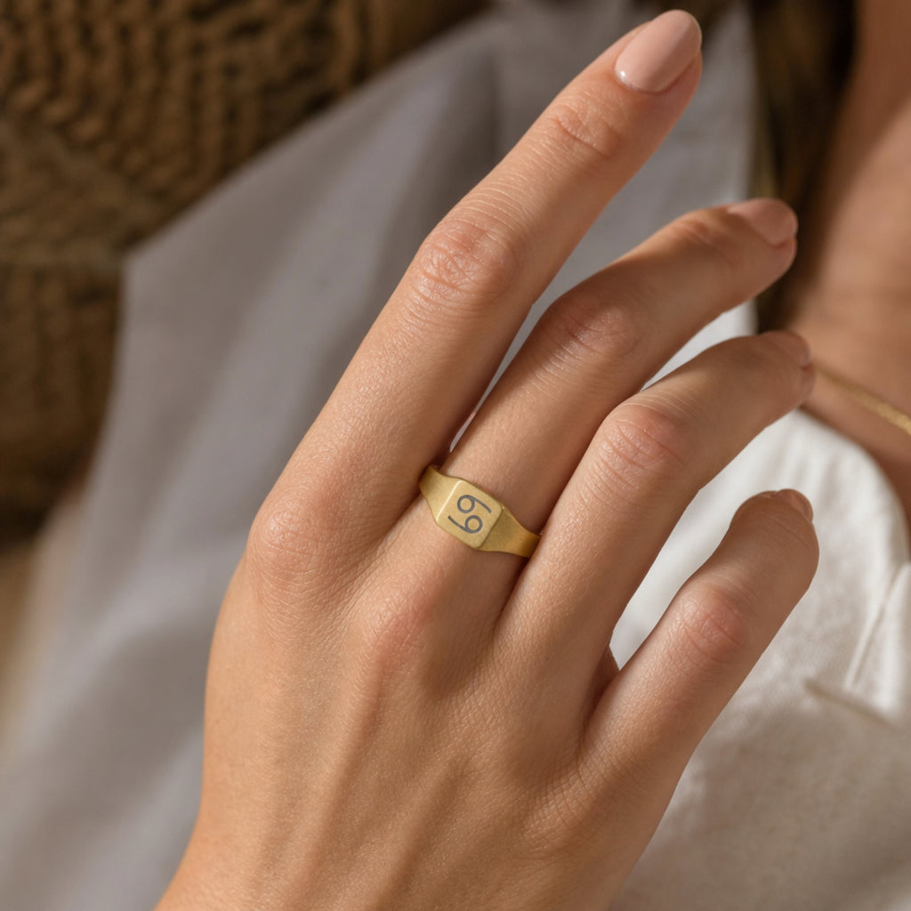 Cancer zodiac square signet ring on finger — model wearing engraved Cancer signet, cream linen lifestyle moment