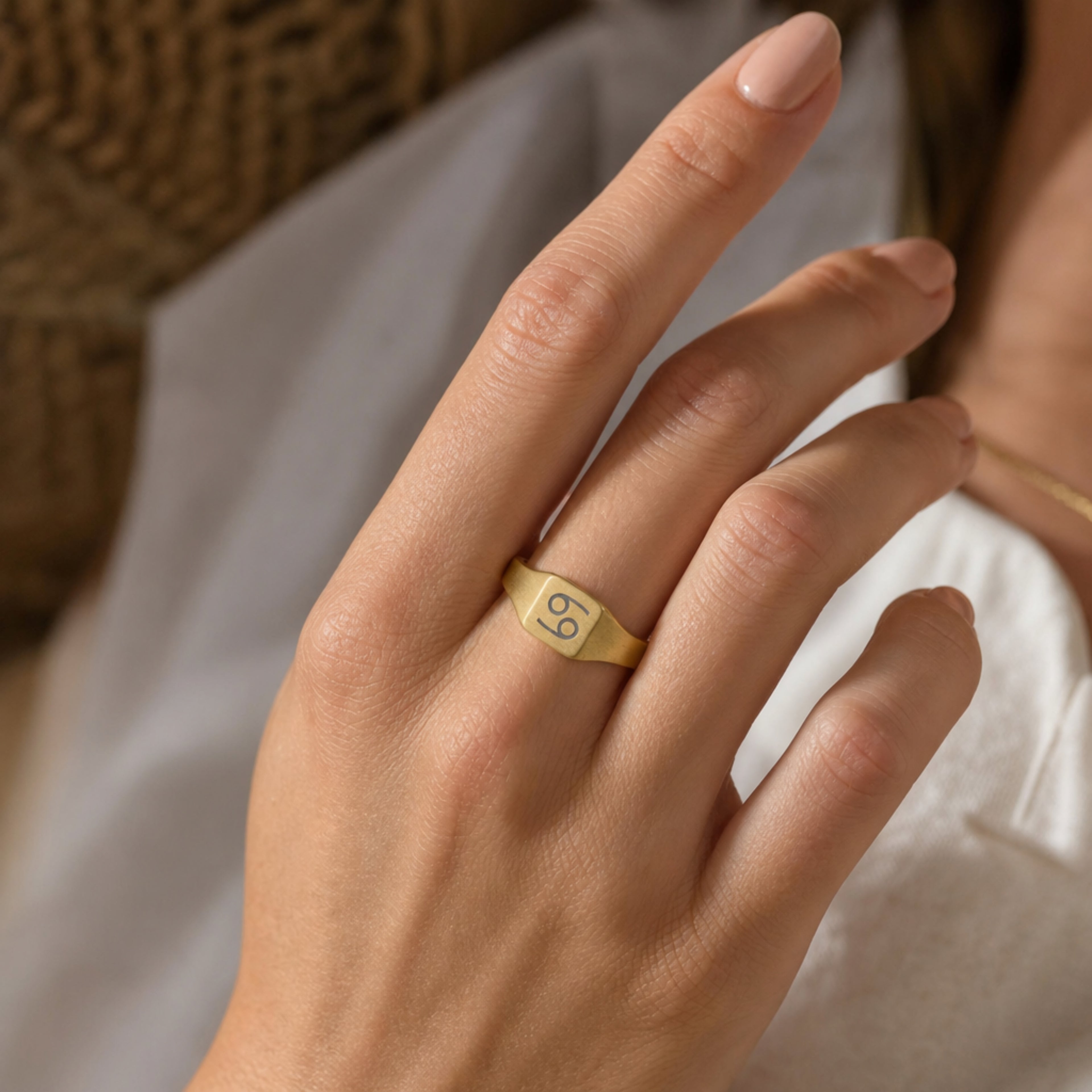 Cancer zodiac square signet ring on finger — model wearing engraved Cancer signet, cream linen lifestyle moment