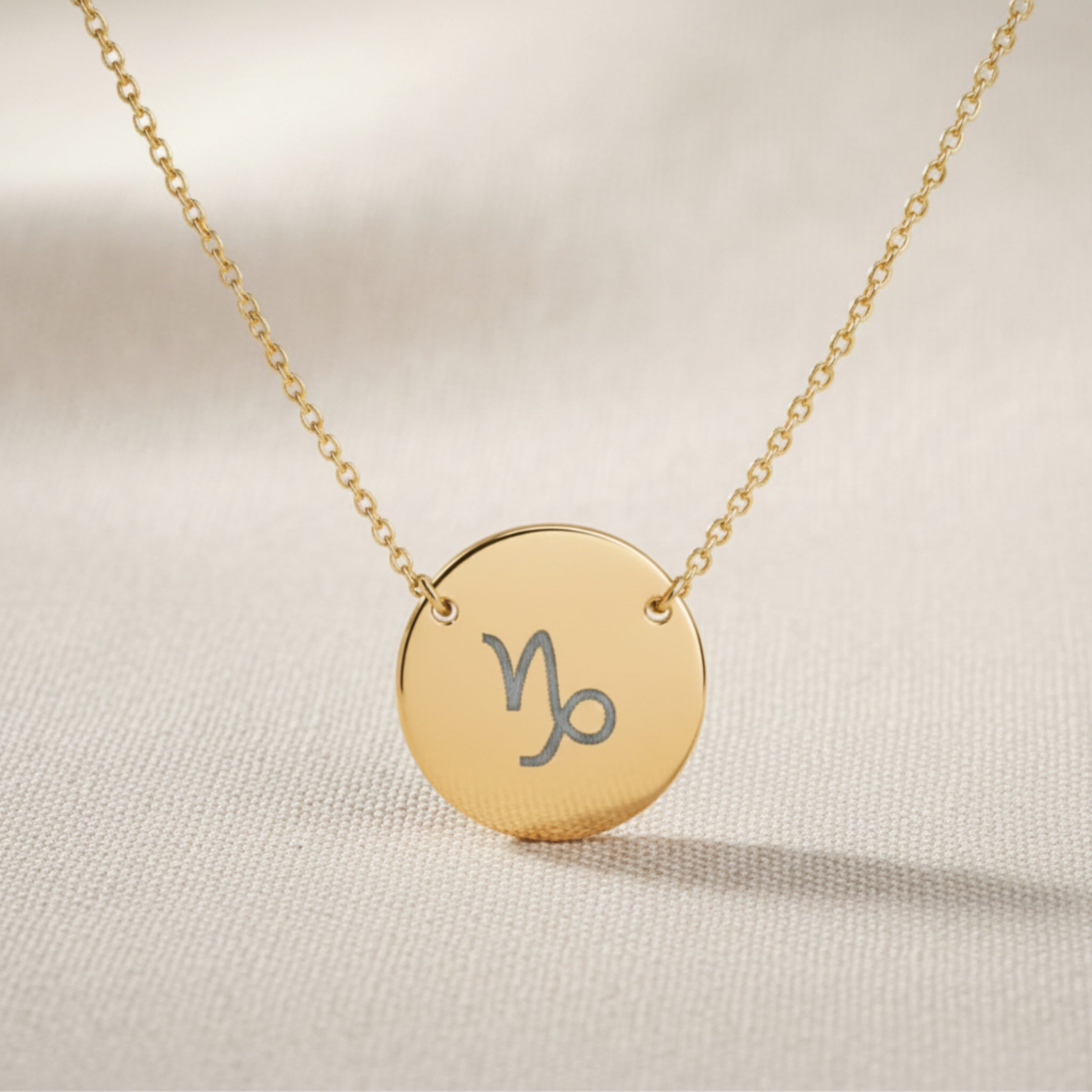 Capricorn zodiac coin necklace close-up — detail of laser-engraved Capricorn Goat glyph on 18K gold pendant