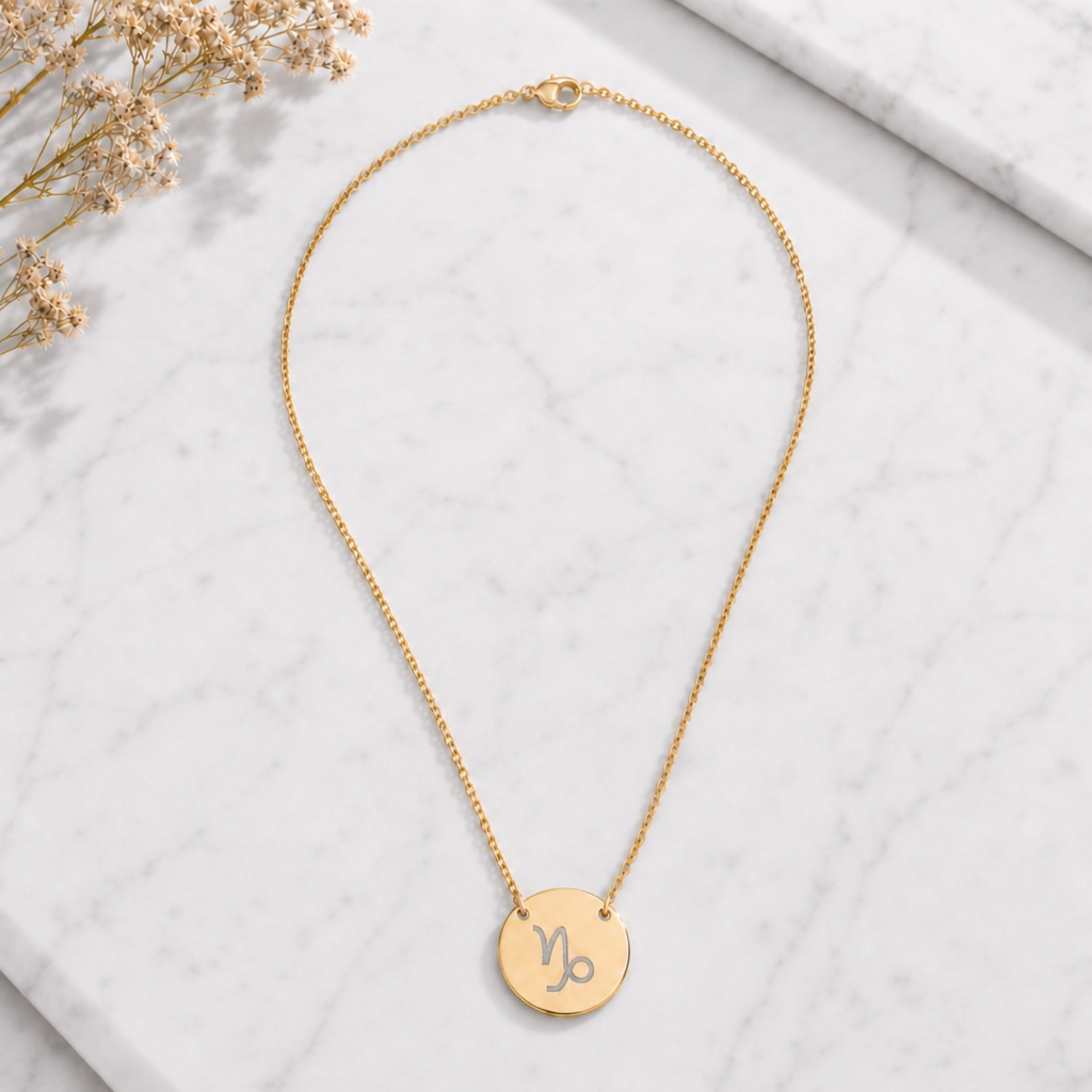 Capricorn zodiac coin necklace marble flatlay — 18K gold pendant engraved with Capricorn Goat star sign on white marble with dried floral, premium personalized astrology necklace gift for January birthday, Capricornian present