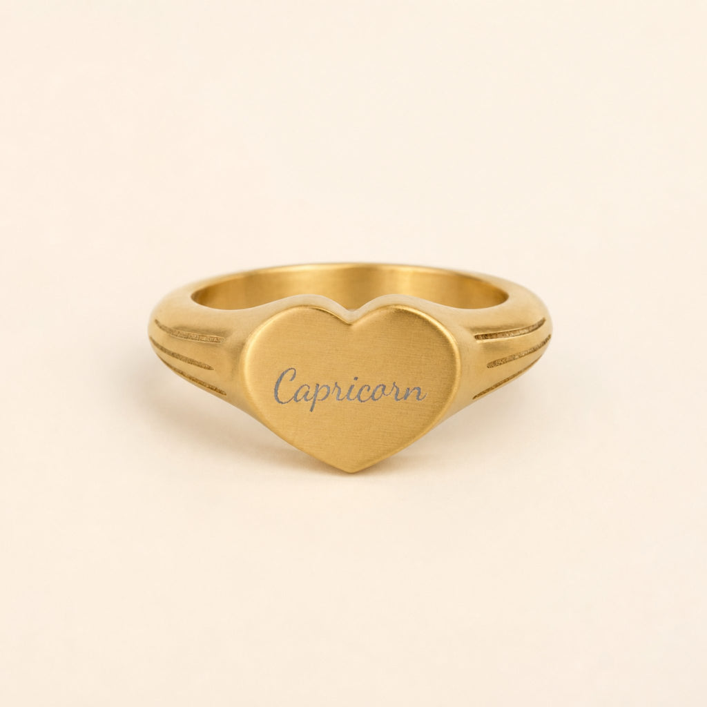 Capricorn zodiac heart signet ring studio front — clean cream backdrop product shot, 18K gold matte PVD