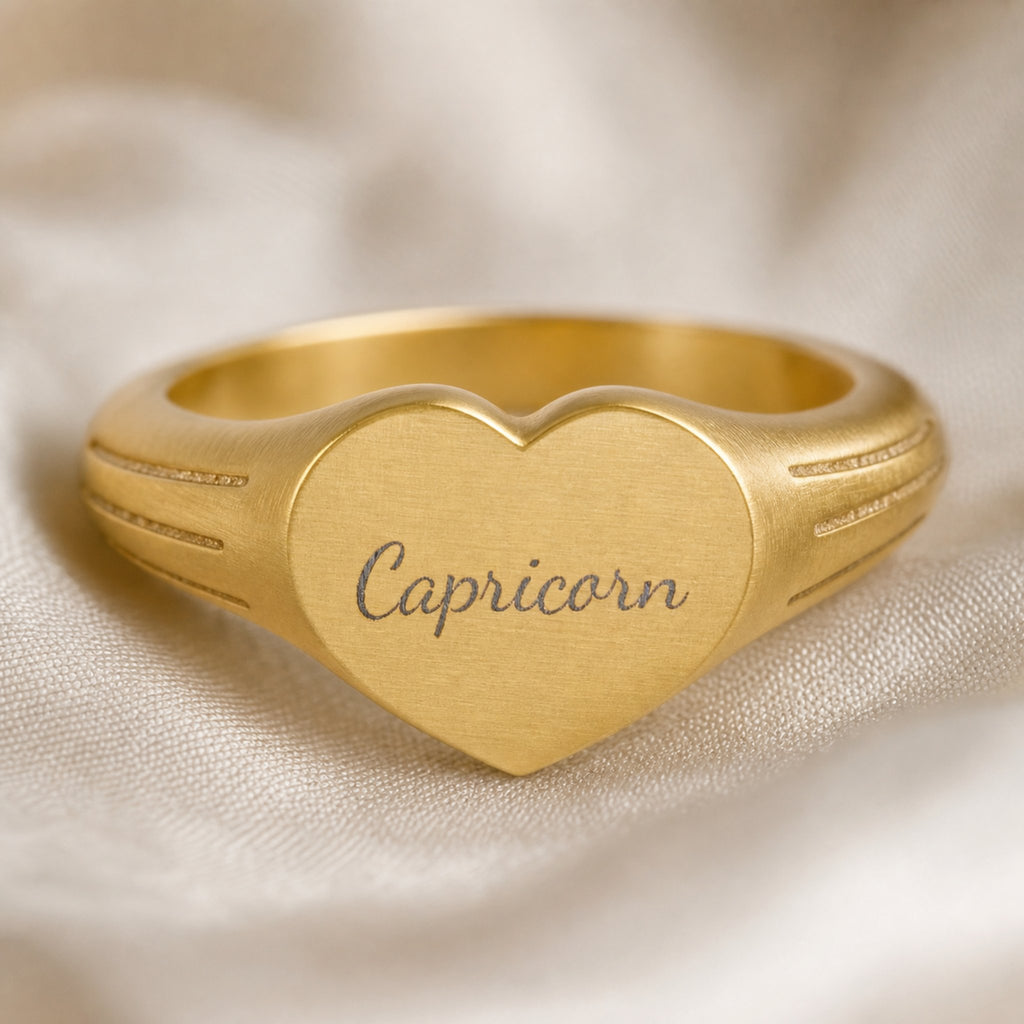 Capricorn zodiac heart signet ring engraving close-up — laser-etched Capricorn name detail, brushed grey cursive on matte gold heart