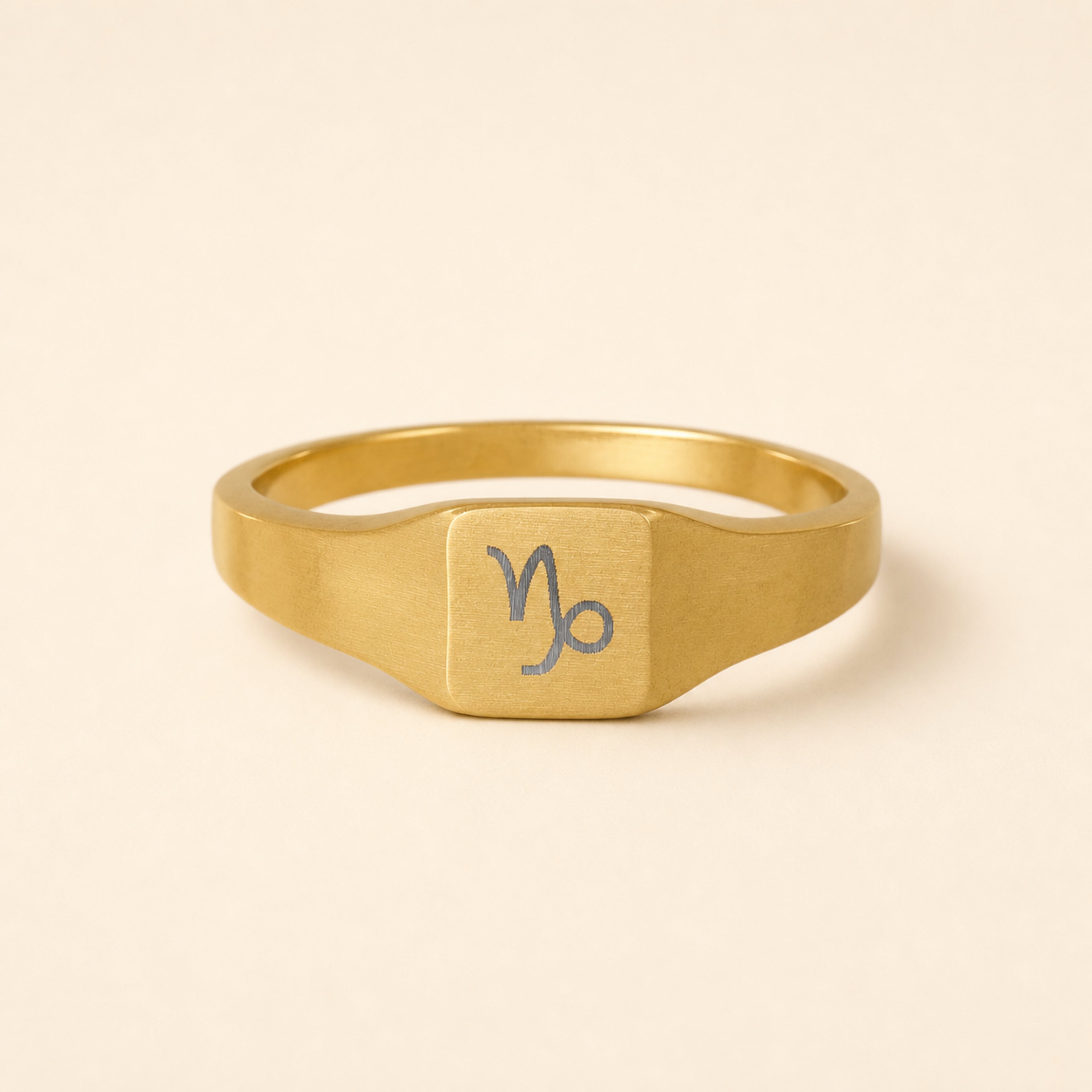 Capricorn zodiac square signet ring studio front — clean cream backdrop product shot, 18K gold matte PVD