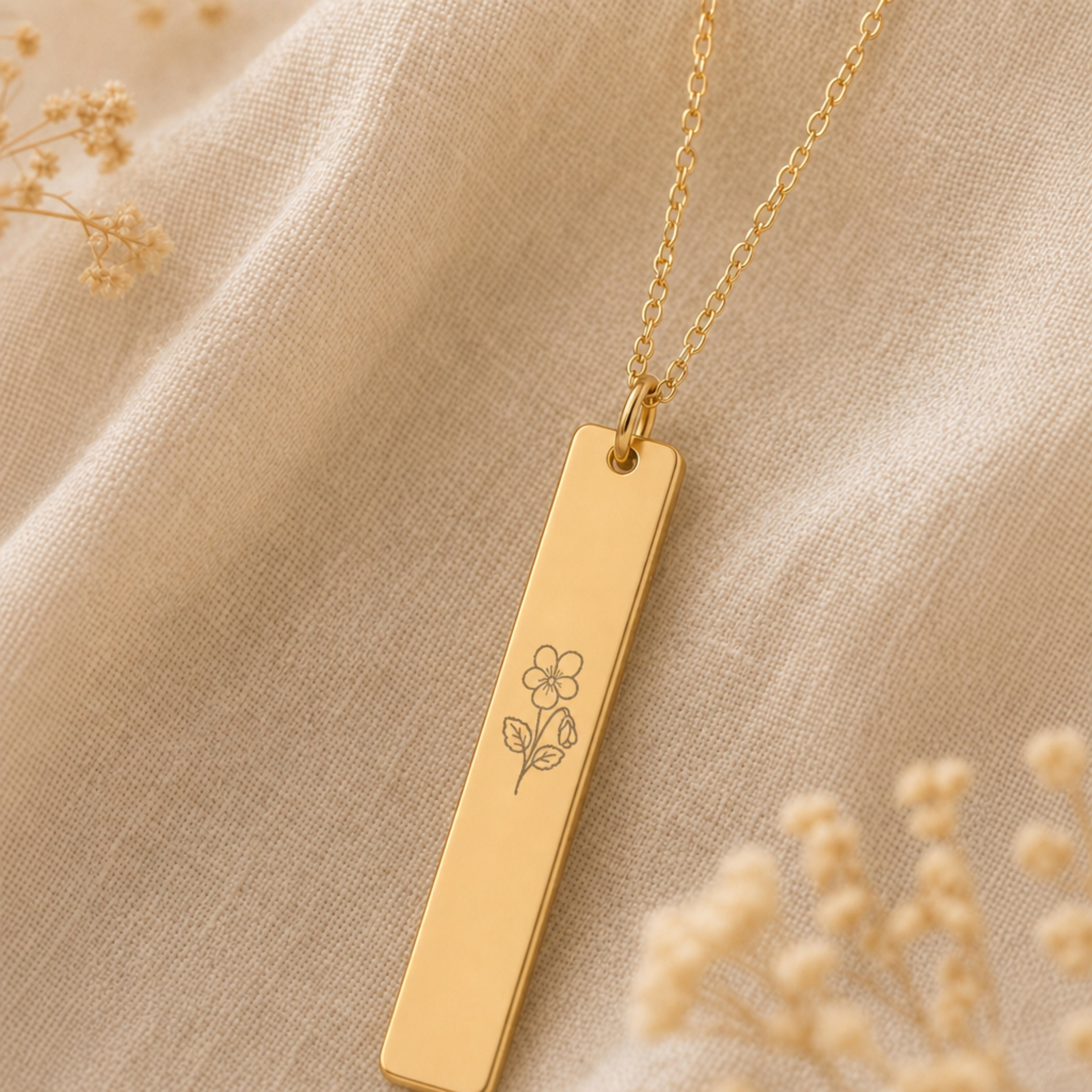February birth flower necklace — Violet engraved vertical bar pendant flatlay with dried botanicals on cream linen, premium editorial styling, 18K Gold PVD on premium 316L stainless steel