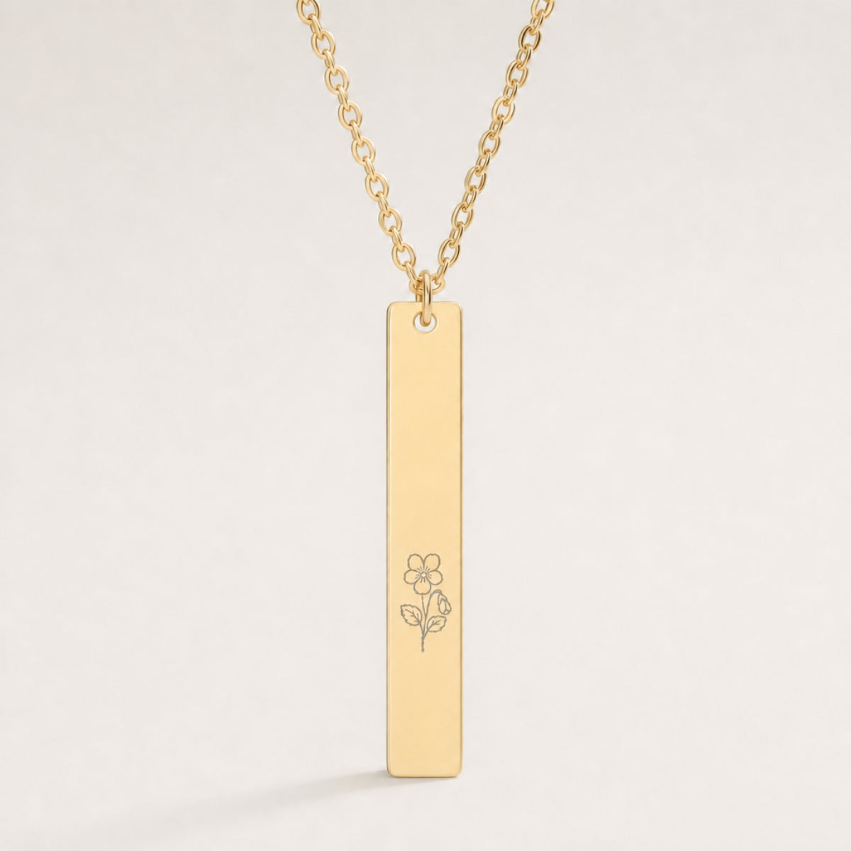 February birth flower necklace — Violet engraved on 1.26" × 0.20" vertical bar pendant, premium close-up macro hero, fine line art laser-etched silhouette in grey/etched matte finish on 18K Gold PVD polished mirror, premium 316L stainless steel