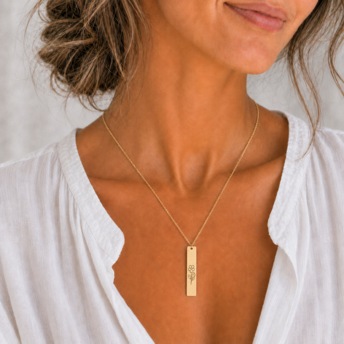 February birth flower necklace — Violet engraved on 1.26" × 0.20" vertical bar pendant, 18K Gold PVD finish, model wearing pendant, on-neck lifestyle, premium 316L stainless steel