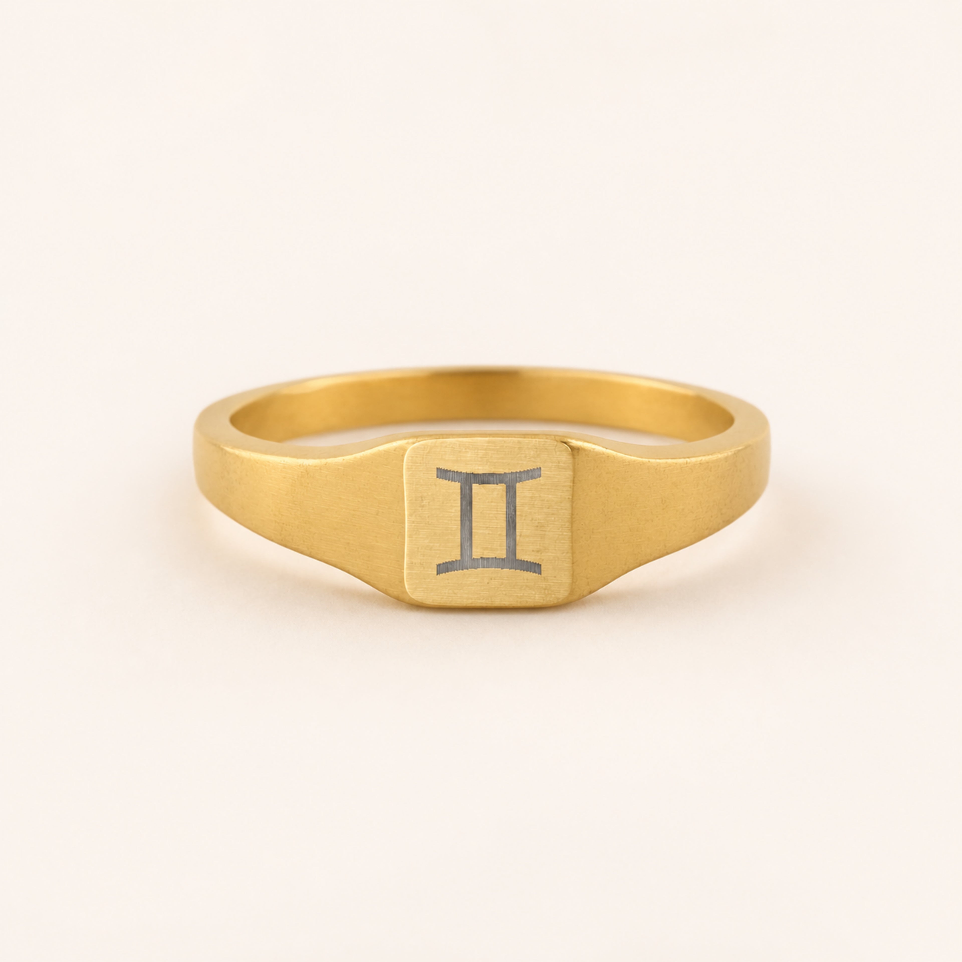 Gemini zodiac square signet ring studio front — clean cream backdrop product shot, 18K gold matte PVD