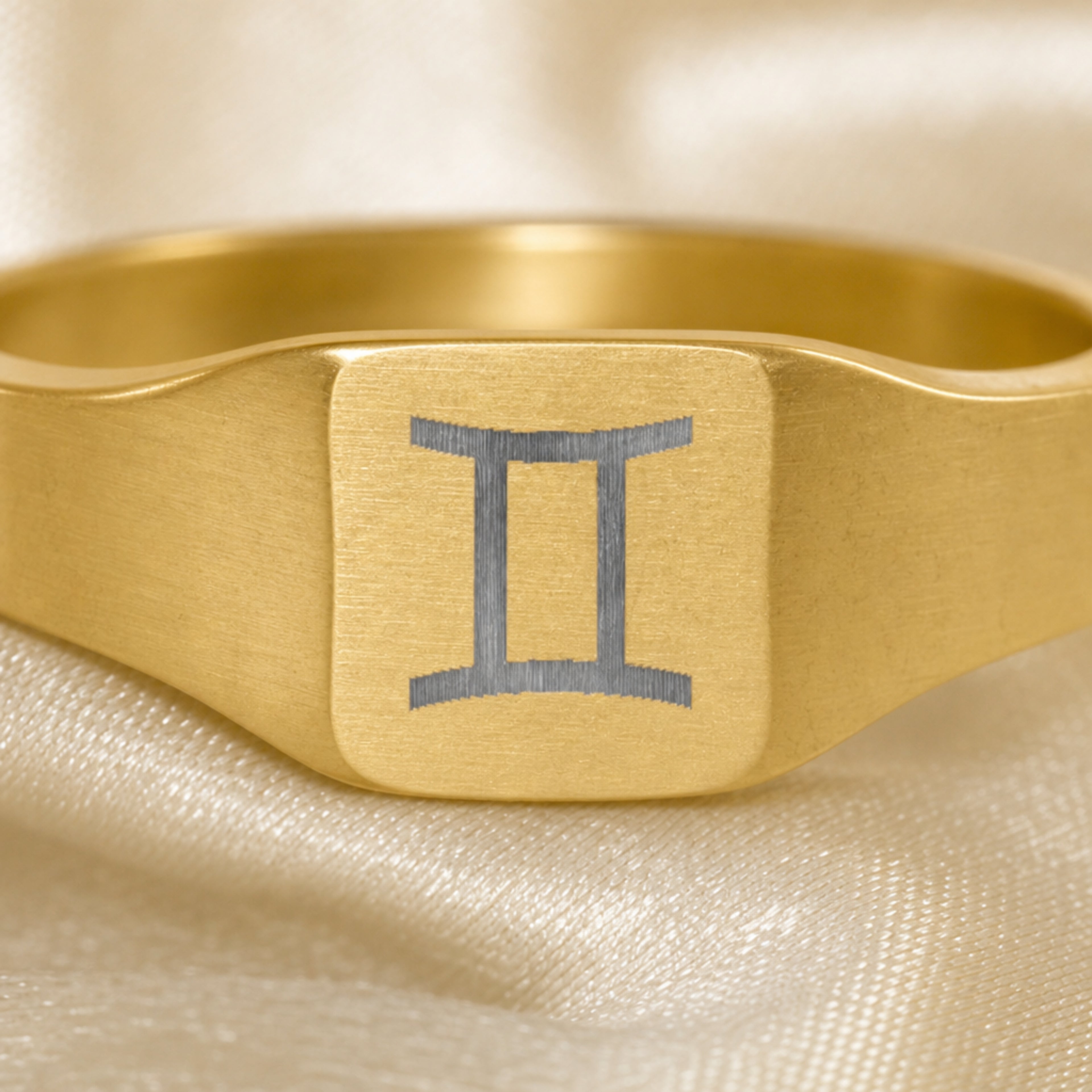 Gemini zodiac square signet ring engraving close-up — laser-etched Twins detail, brushed grey on matte gold