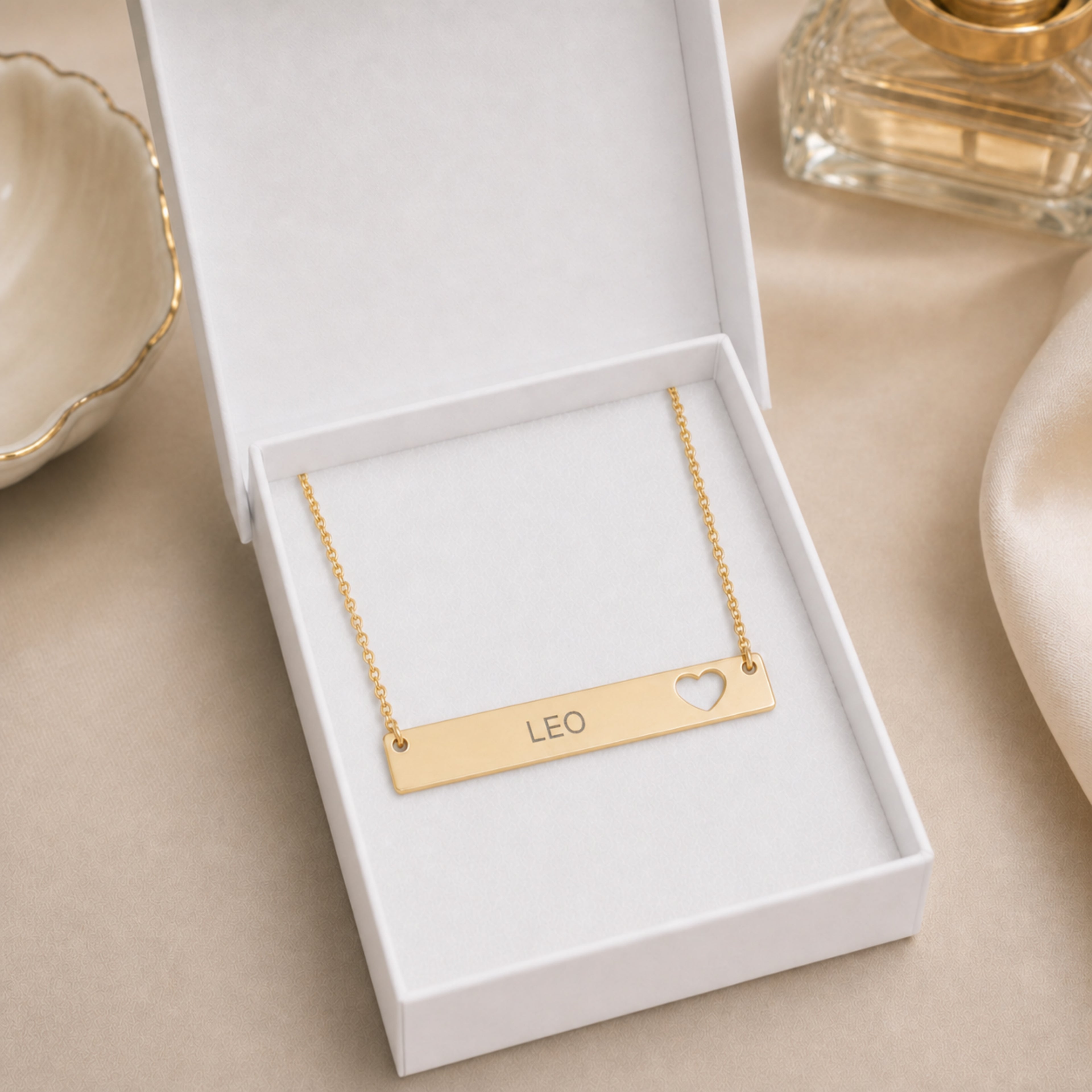 The Leo zodiac necklace nestled in Memory That Lasts signature cream gift box — 18K Gold cutout heart bar pendant with grey laser-etched LEO, premium unboxing moment (AI-generated image)