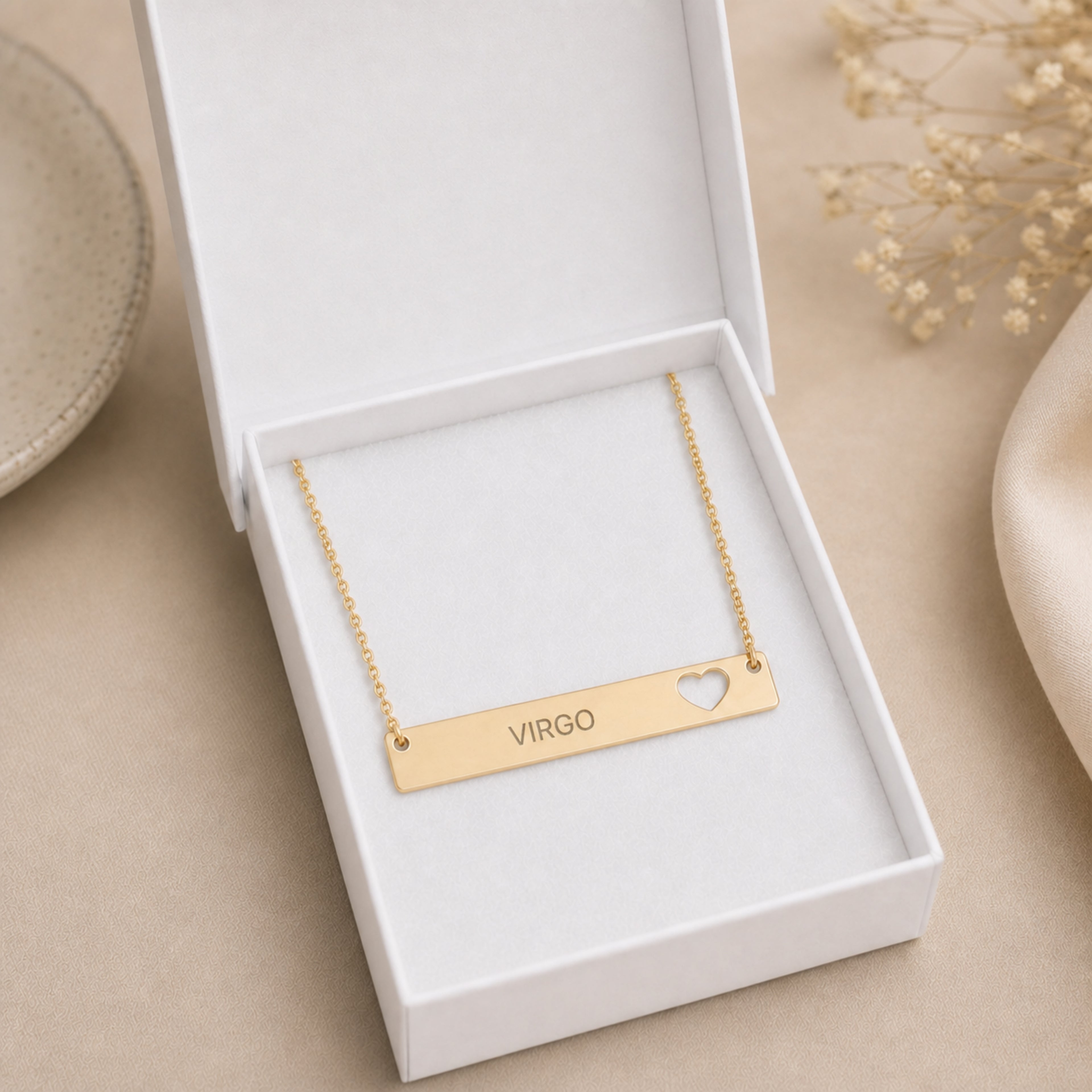 The Virgo zodiac necklace nestled in Memory That Lasts signature cream gift box — 18K Gold cutout heart bar pendant with grey laser-etched VIRGO, premium unboxing moment (AI-generated image)