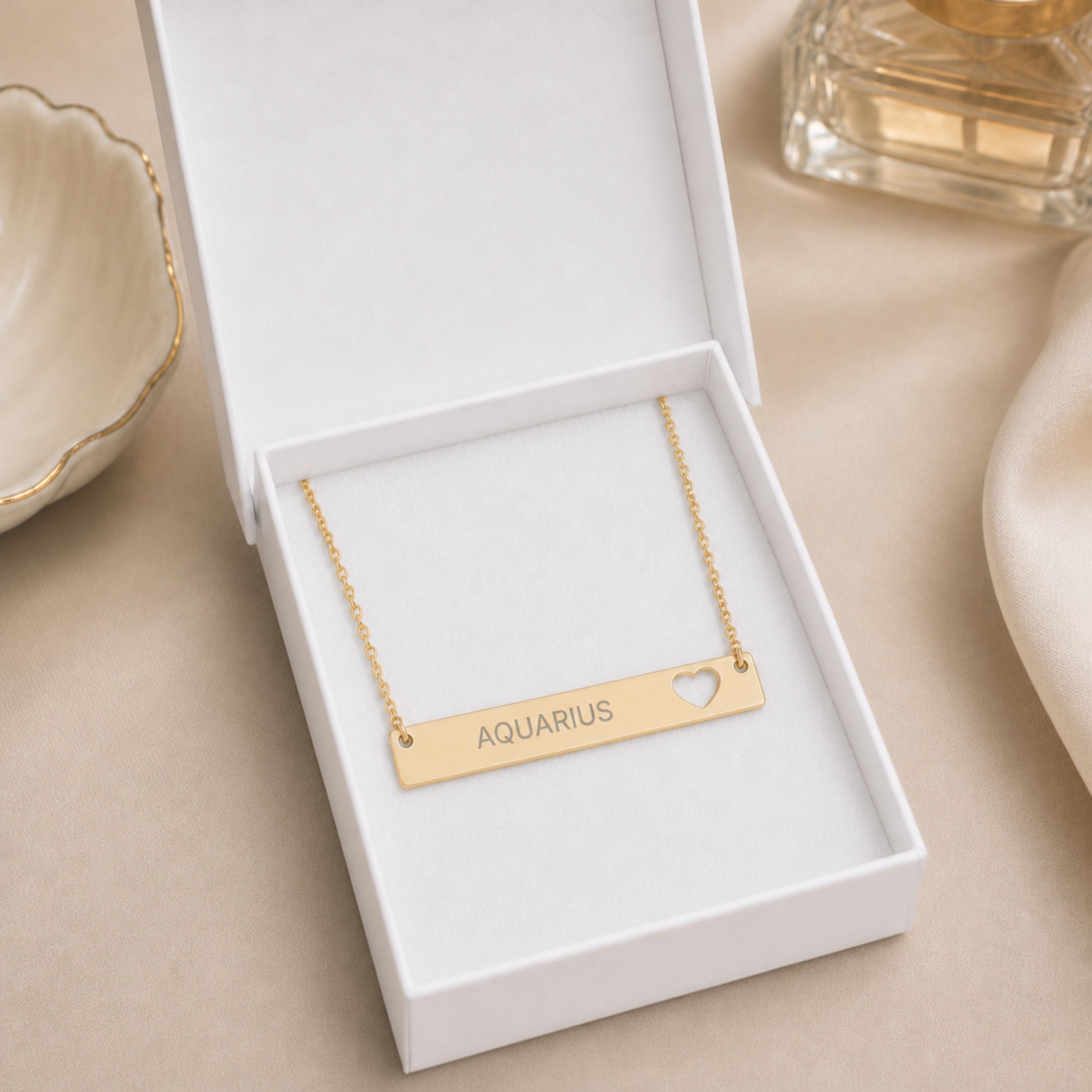 The Aquarius zodiac necklace nestled in Memory That Lasts signature cream gift box — 18K Gold cutout heart bar pendant with grey laser-etched AQUARIUS, premium unboxing moment (AI-generated image)