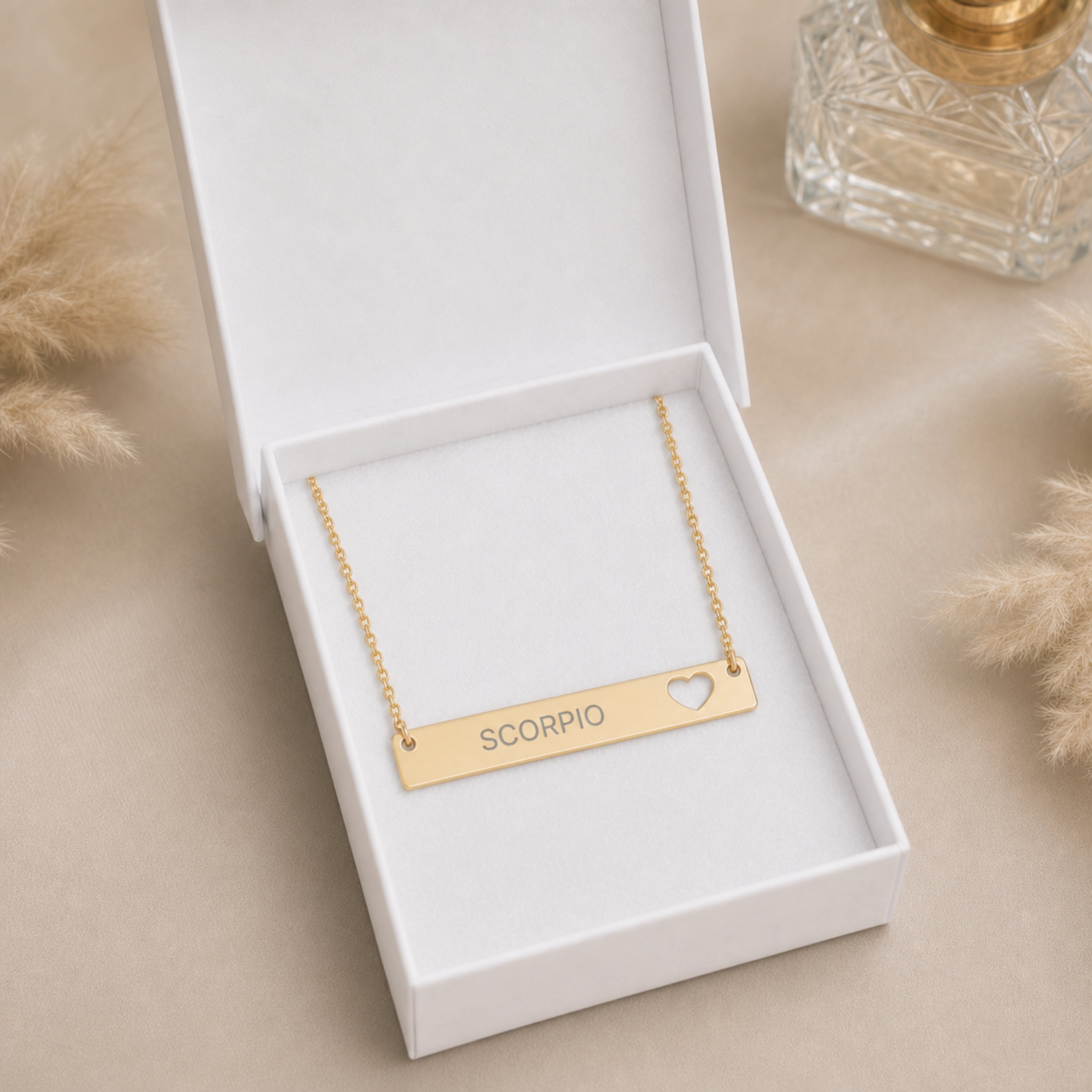 The Scorpio zodiac necklace nestled in Memory That Lasts signature cream gift box — 18K Gold cutout heart bar pendant with grey laser-etched SCORPIO, premium unboxing moment (AI-generated image)