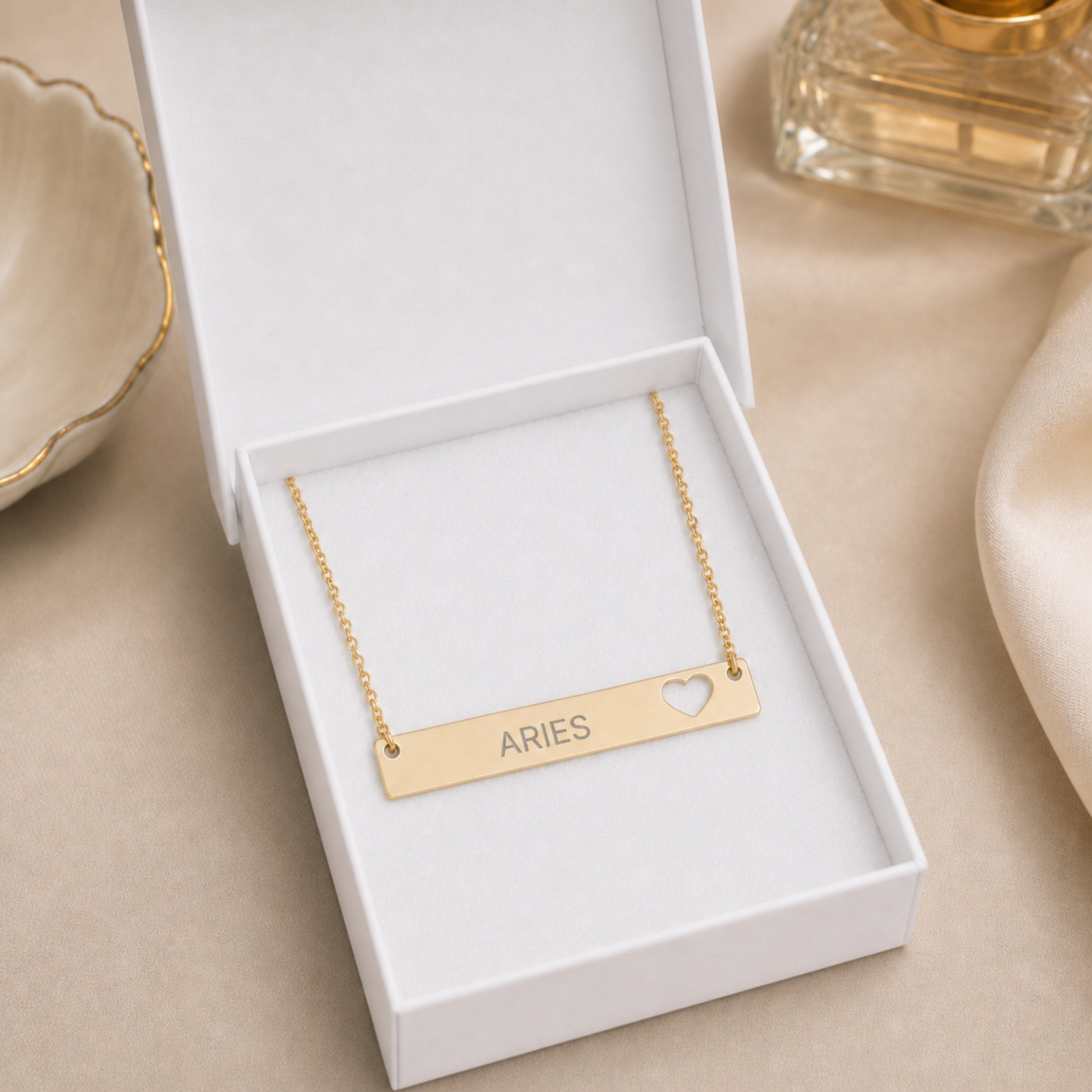 The Aries zodiac necklace nestled in Memory That Lasts signature cream gift box — 18K Gold cutout heart bar pendant with grey laser-etched ARIES, premium unboxing moment (AI-generated image)