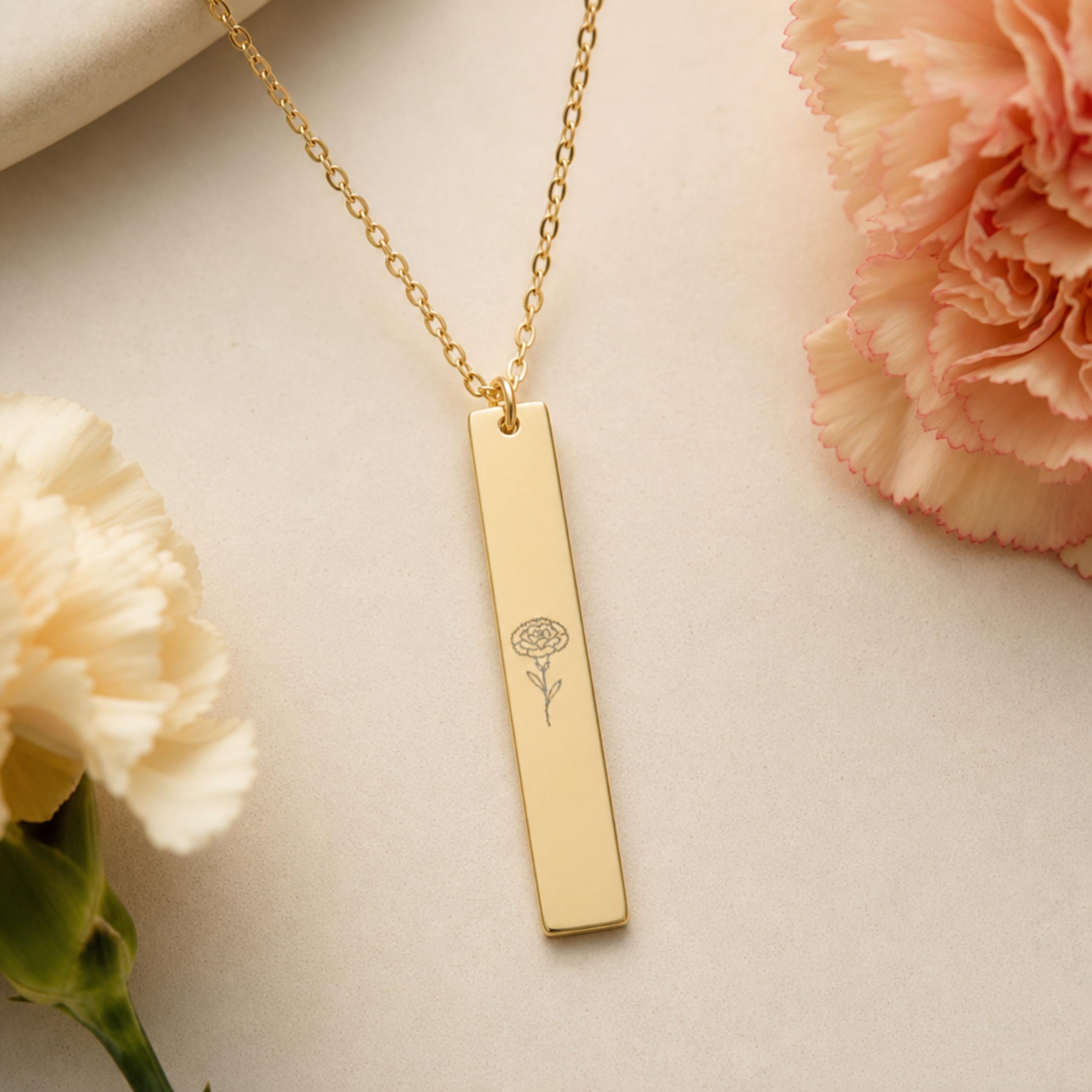 January birth flower necklace — Carnation engraved vertical bar pendant flatlay with real carnation blooms on cream linen, 18K Gold PVD, 316L stainless steel
