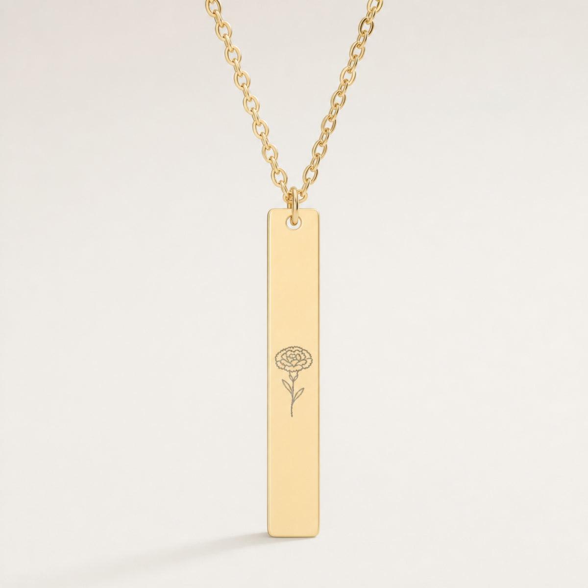 January birth flower necklace — Carnation engraved on 1.26" × 0.20" vertical bar pendant, premium close-up macro hero, fine line art laser-etched silhouette in grey/etched matte finish on 18K Gold PVD polished mirror, premium 316L stainless steel