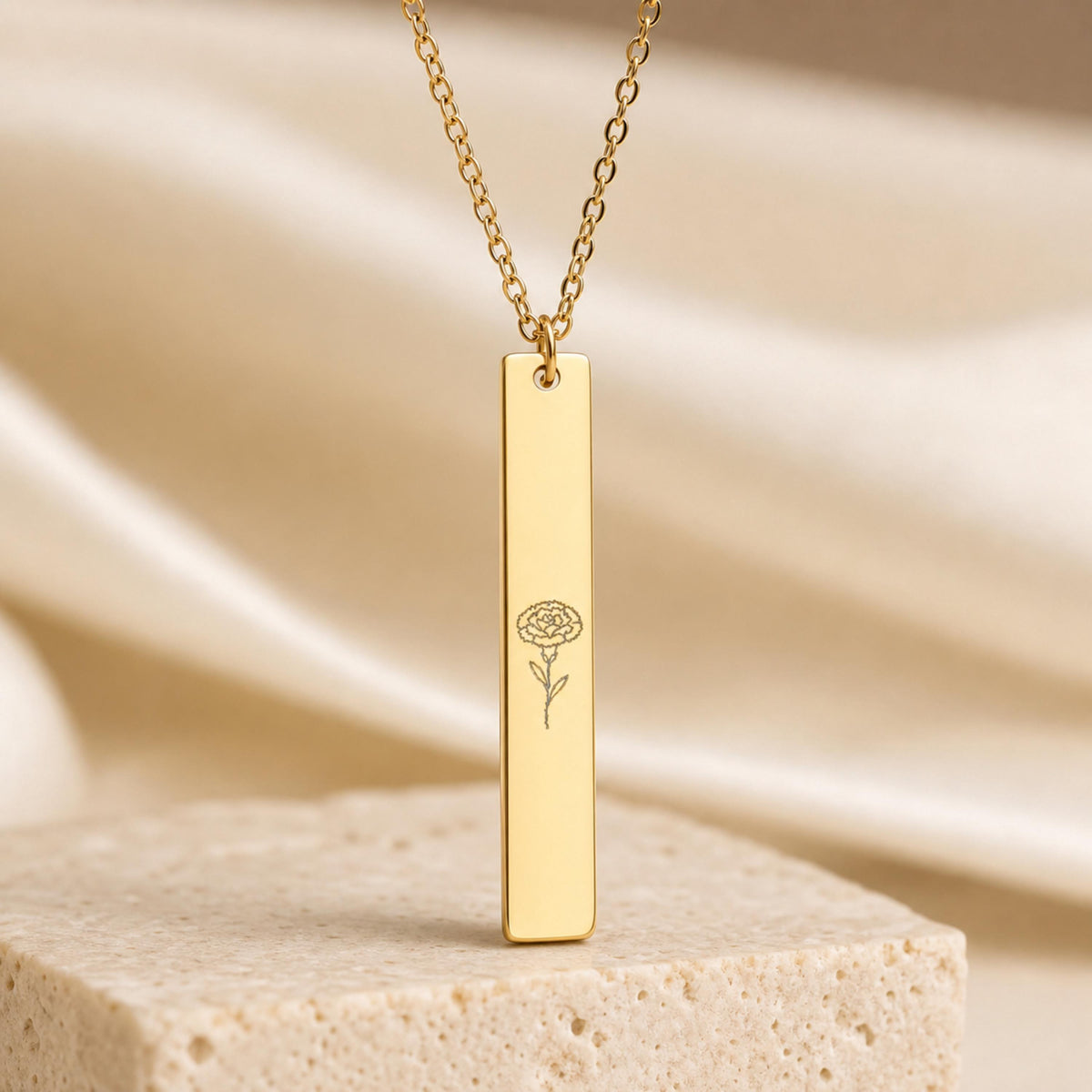 January birth flower necklace — Carnation engraved vertical bar pendant, 18K Gold PVD, premium pedestal product hero, 316L stainless steel