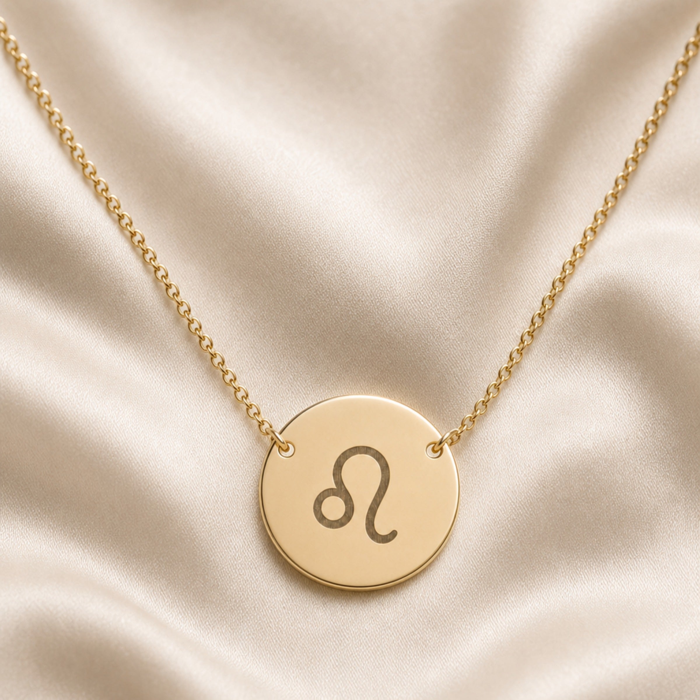 Leo Coin Gold zodiac necklace flatlay — 18K gold pendant engraved with Leo Lion star sign on cream silk, premium personalized astrology necklace gift for August birthday, Leo woman, mother, daughter