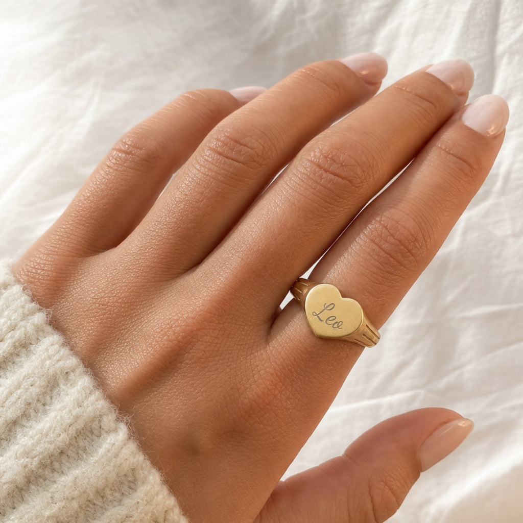Leo zodiac heart signet ring on finger — model wearing engraved Leo heart signet, cream linen lifestyle moment