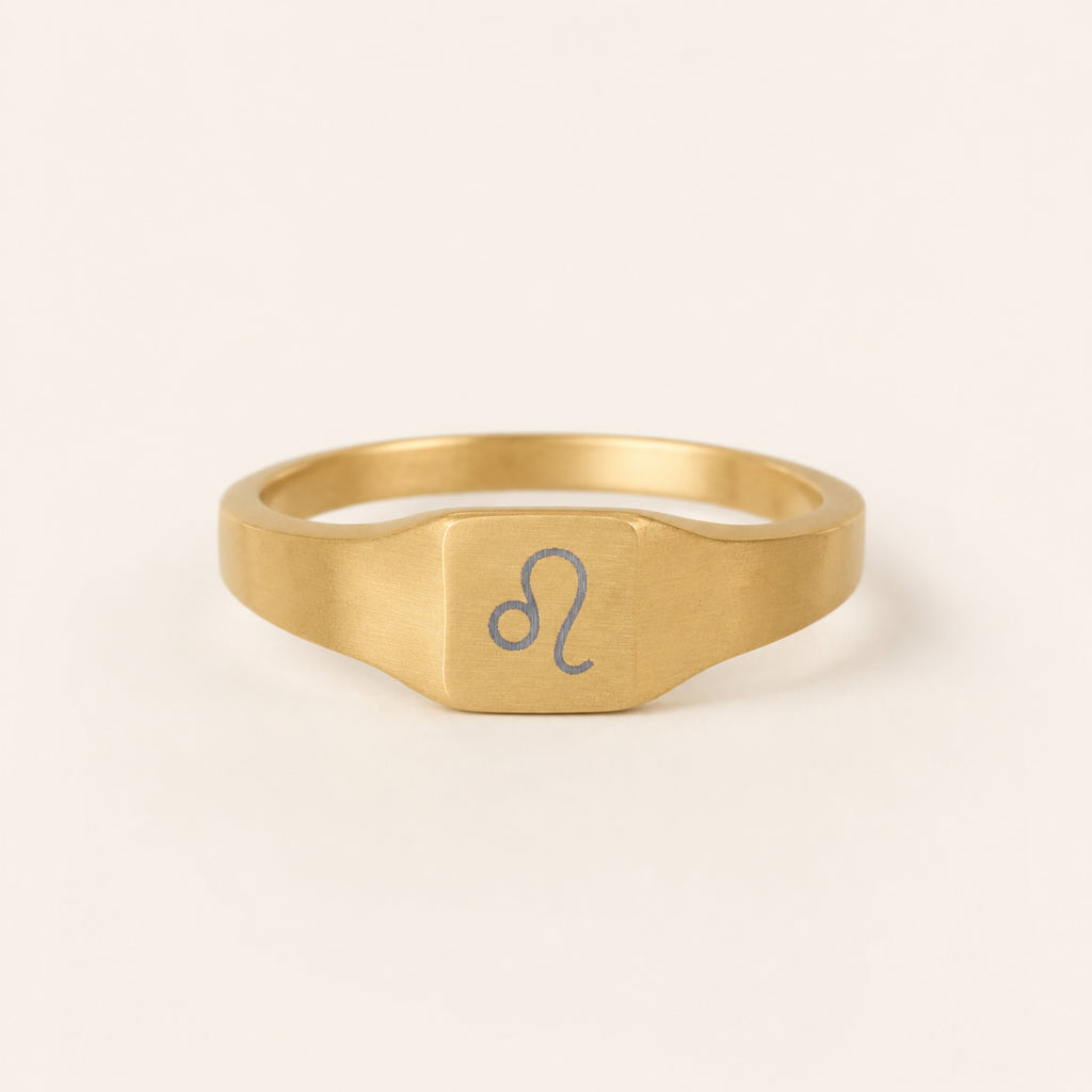 Leo zodiac square signet ring studio front — clean cream backdrop product shot, 18K gold matte PVD