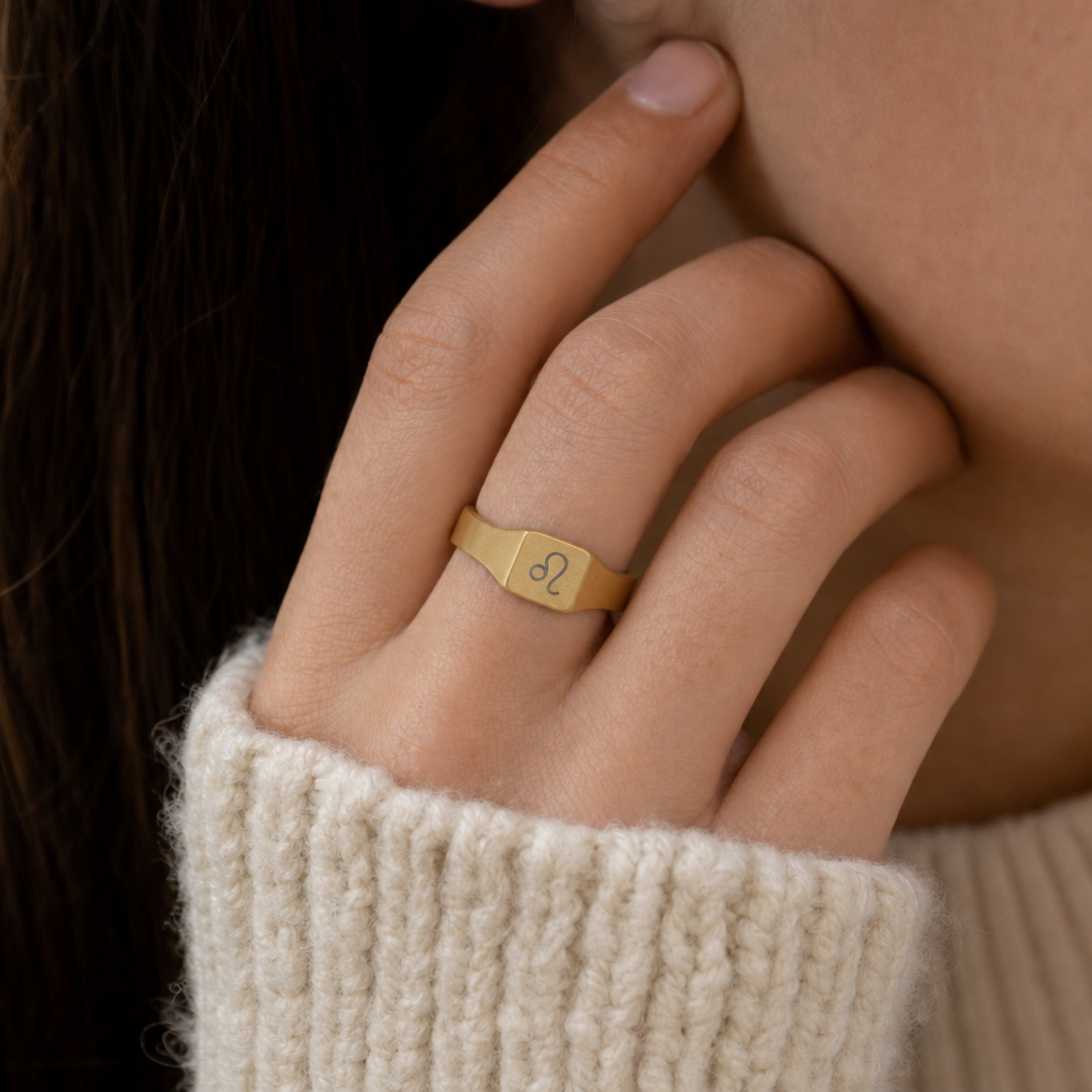 Leo zodiac square signet ring on finger — model wearing engraved Leo signet, cream linen lifestyle moment
