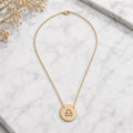 Libra zodiac coin necklace marble flatlay — 18K gold pendant engraved with Libra Scales star sign on white marble with dried floral, premium personalized astrology necklace gift for October birthday, Libraian present