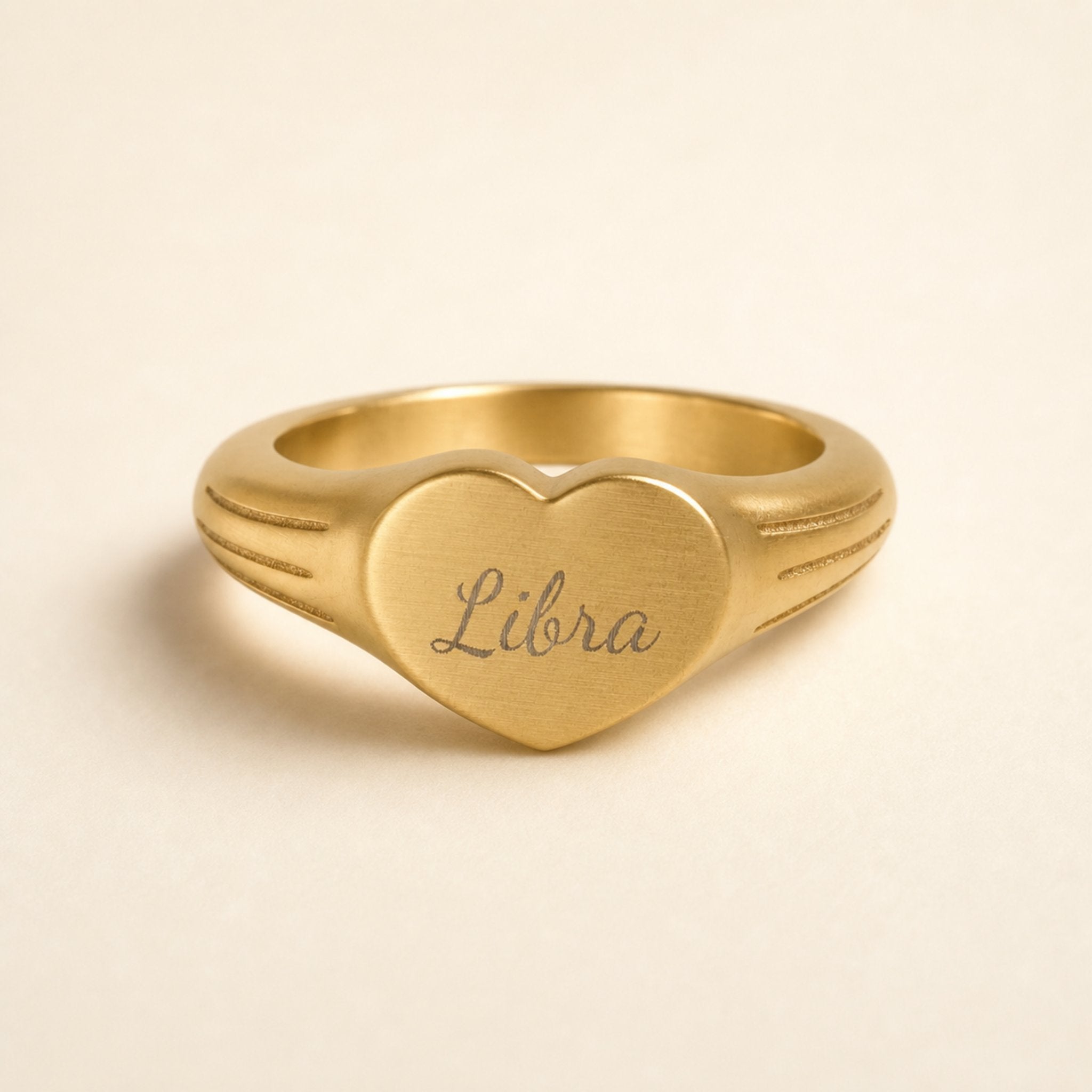 Libra zodiac heart signet ring studio front — clean cream backdrop product shot, 18K gold matte PVD
