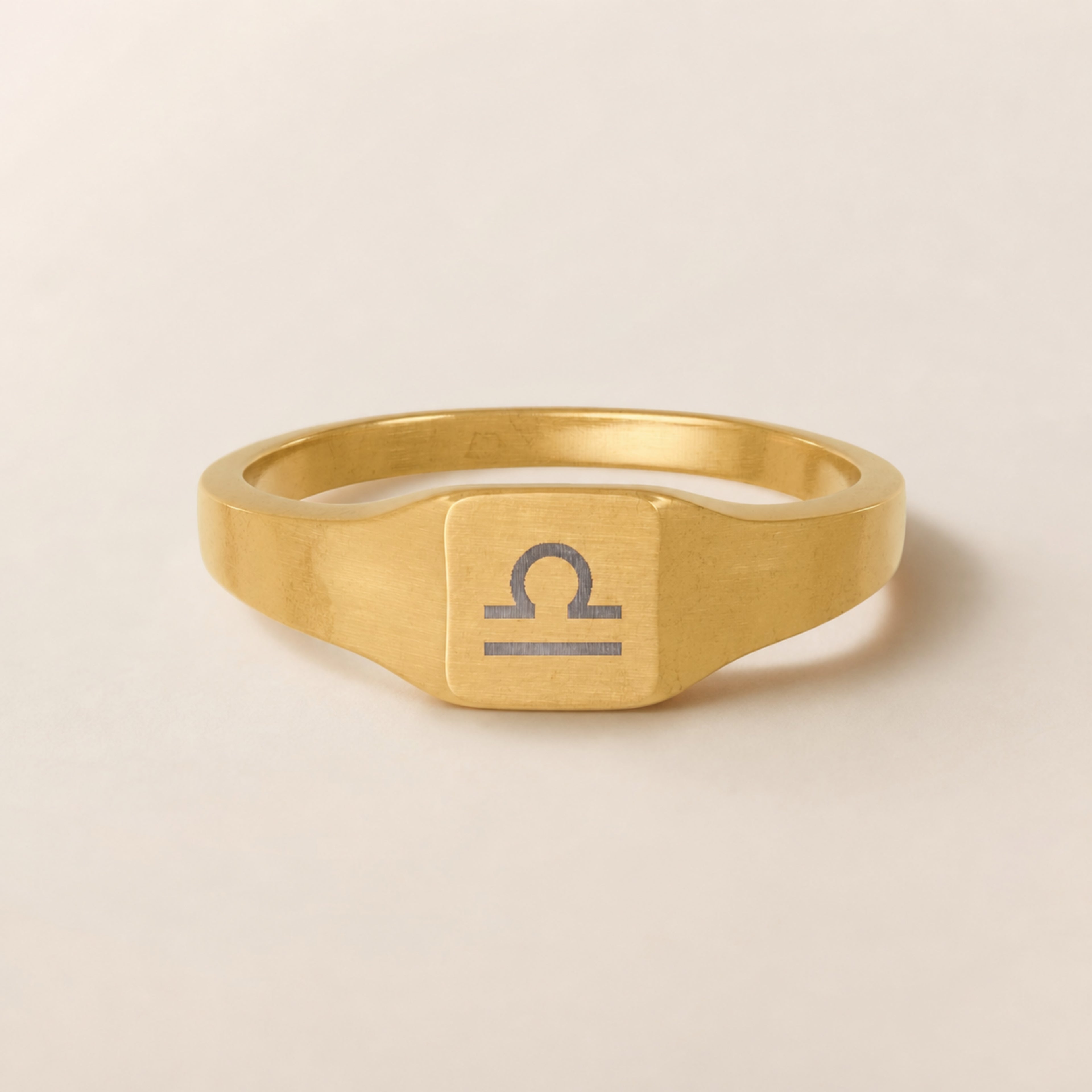 Libra zodiac square signet ring studio front — clean cream backdrop product shot, 18K gold matte PVD