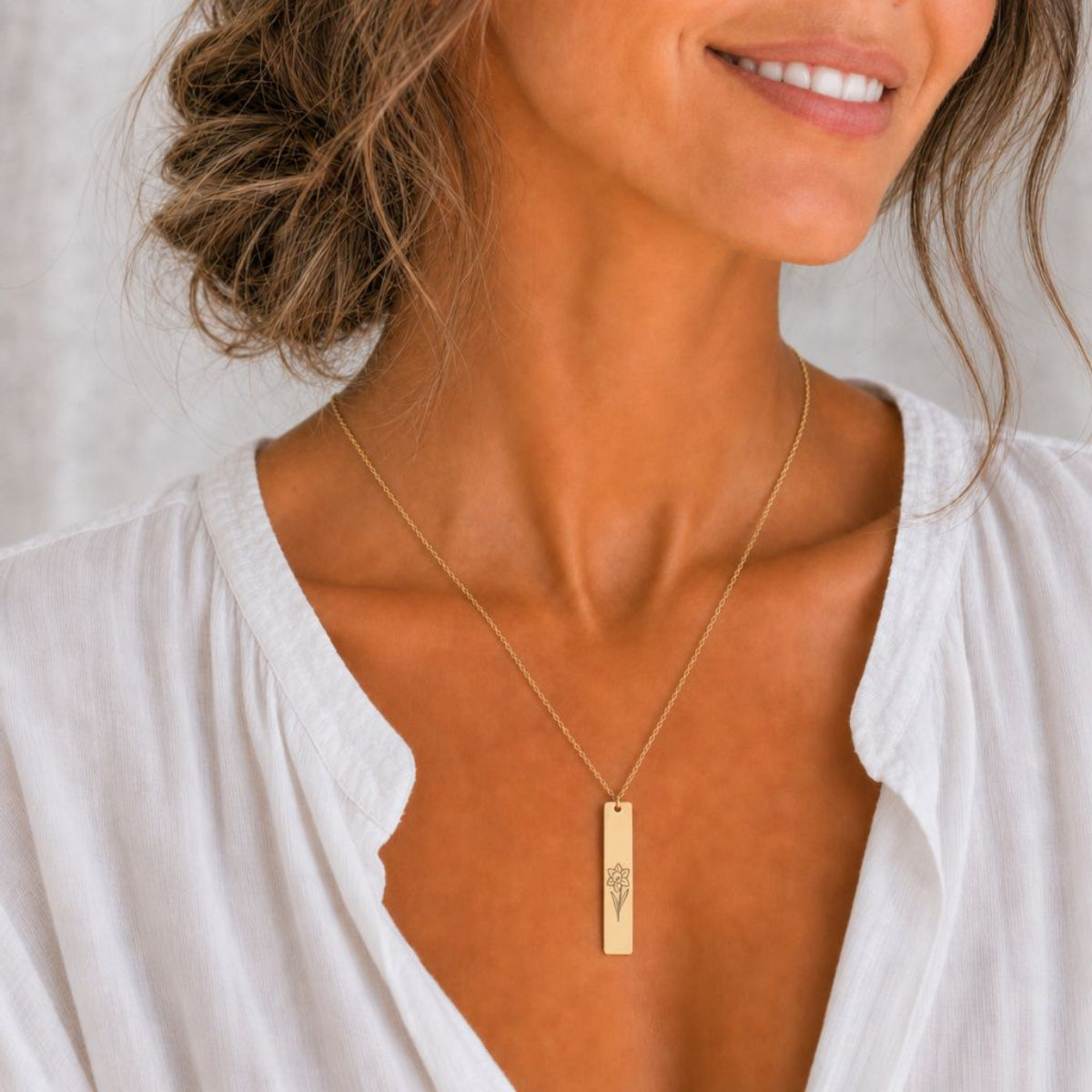 March birth flower necklace — Daffodil engraved on 1.26" × 0.20" vertical bar pendant, 18K Gold PVD finish, model wearing pendant, on-neck lifestyle, premium 316L stainless steel