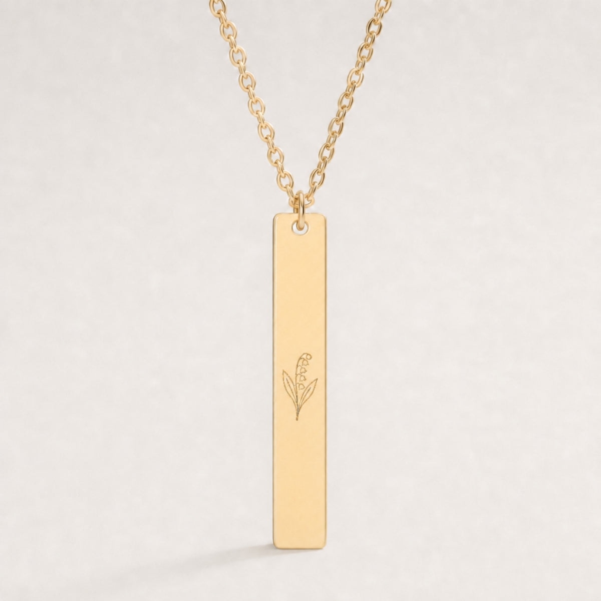 May birth flower necklace — Lily of the Valley engraved on 1.26" × 0.20" vertical bar pendant, premium close-up macro hero on 18K Gold PVD
