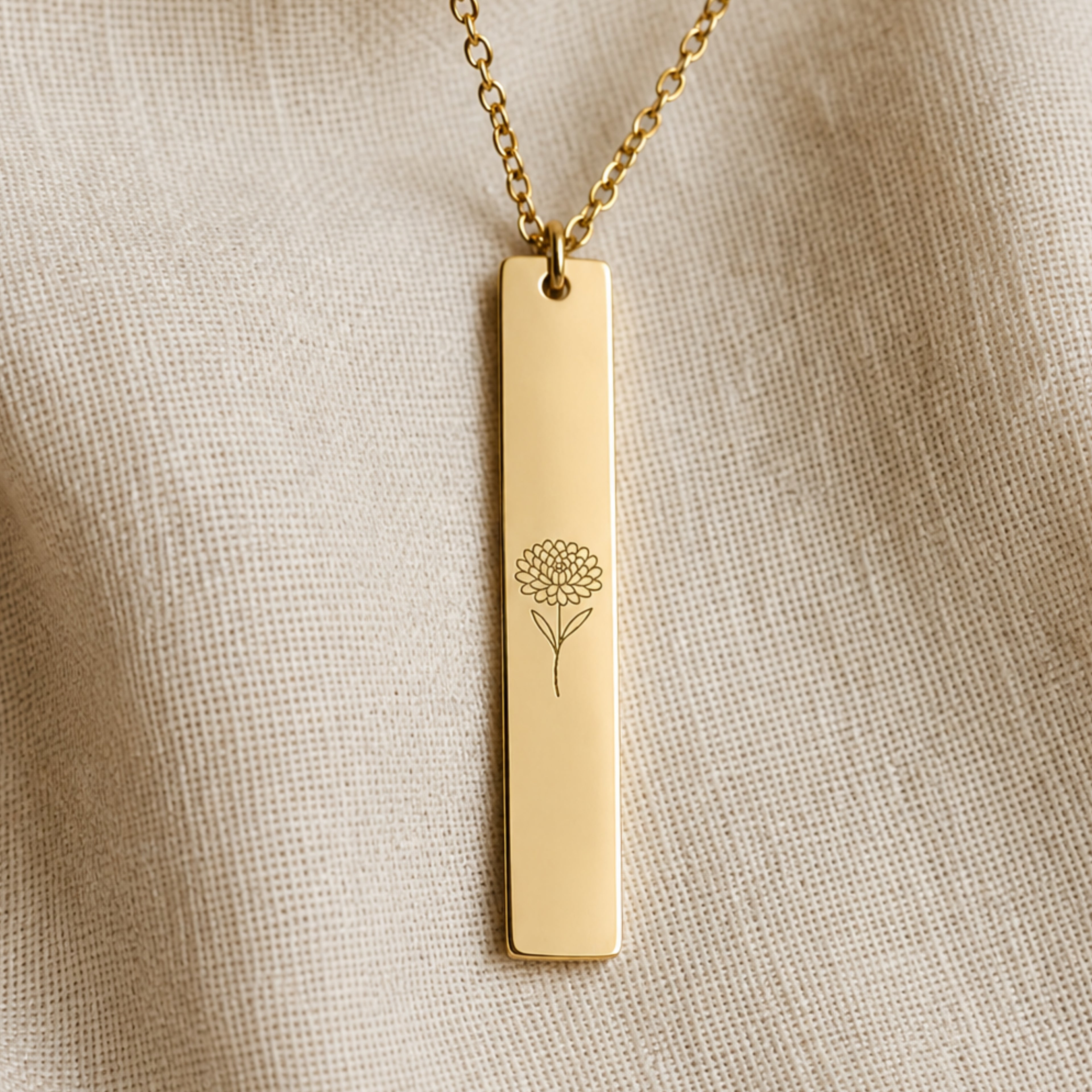 November birth flower necklace — Chrysanthemum engraved vertical bar pendant flatlay with dried botanicals on cream linen