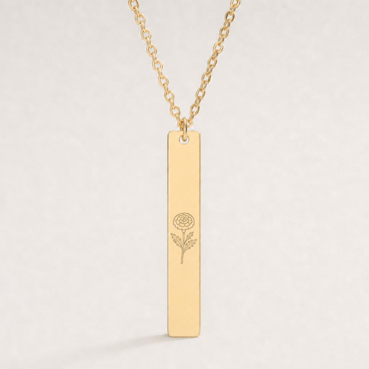 October birth flower necklace — Marigold engraved on 1.26" × 0.20" vertical bar pendant, premium close-up macro hero on 18K Gold PVD