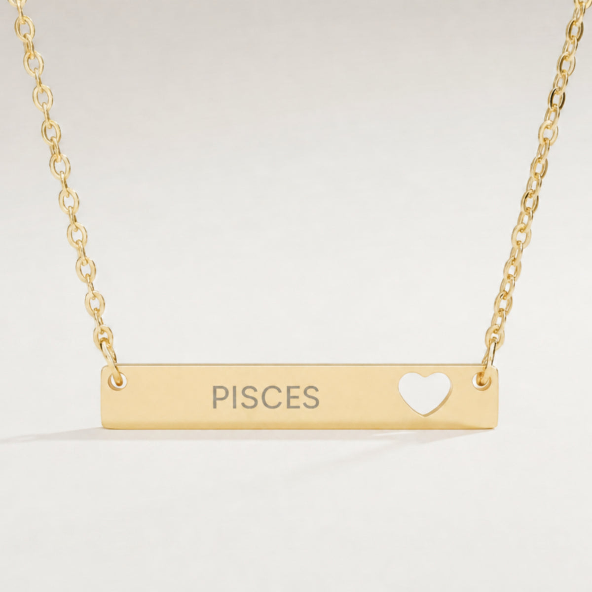 Pisces zodiac necklace close-up — 18K Gold polished cutout heart bar pendant with grey laser-etched PISCES, see-through heart cutout, premium macro on white background
