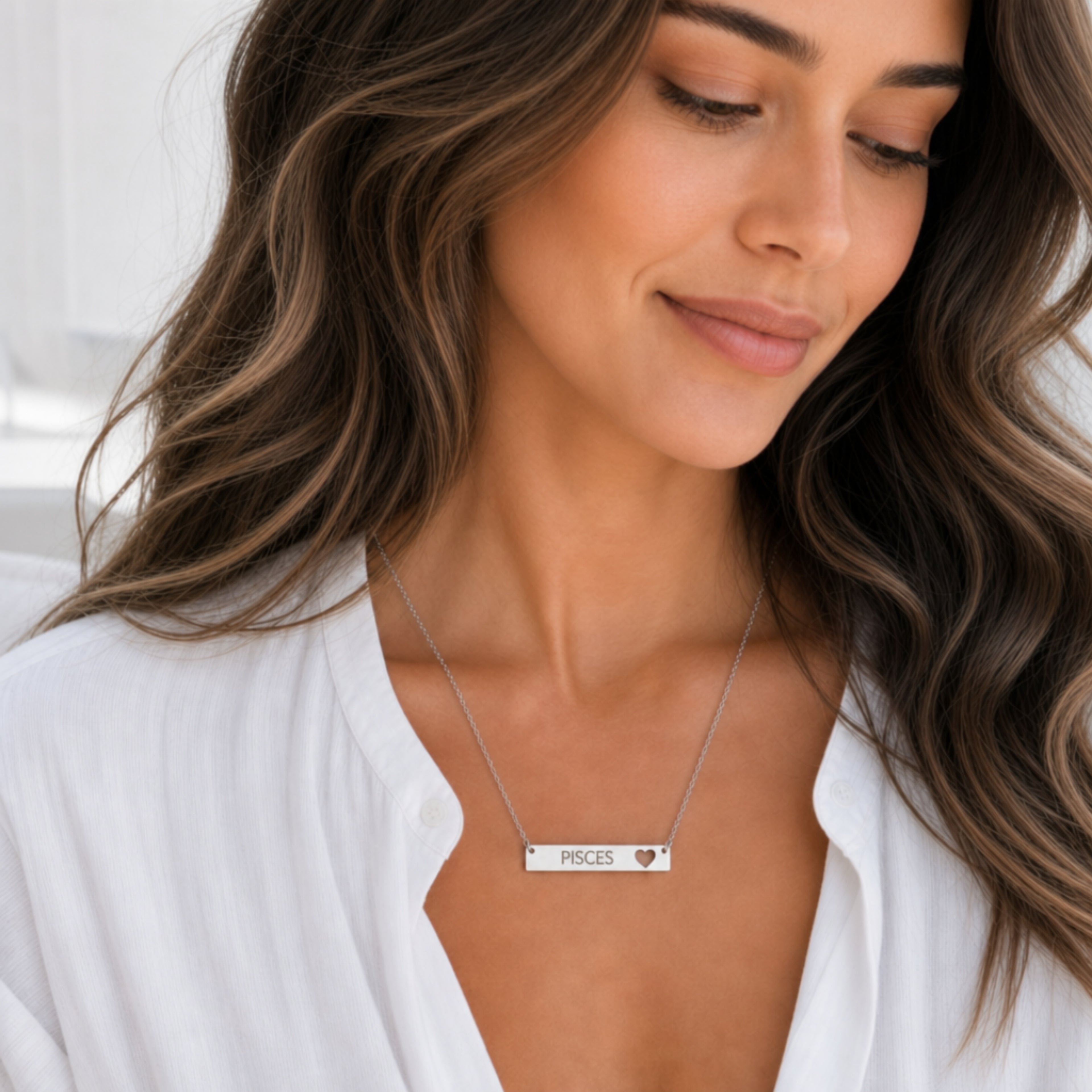 Model wearing the Pisces zodiac necklace in 316L stainless steel — polished mirror cutout heart bar with grey laser-etched PISCES, see-through heart cutout, white blouse, soft natural daylight