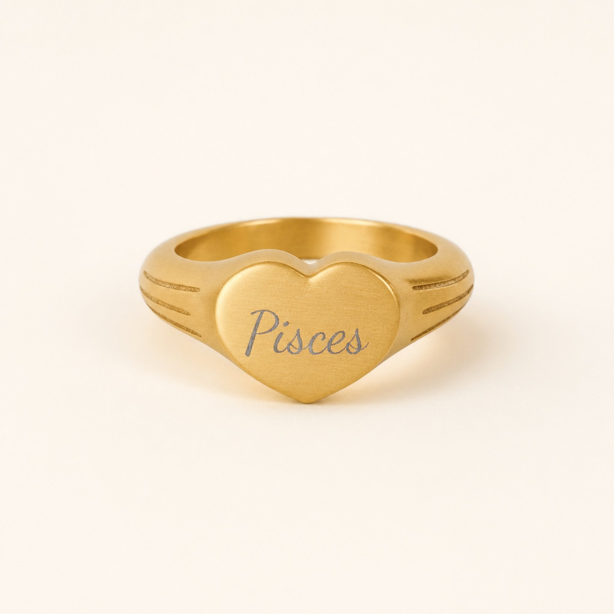 Pisces zodiac heart signet ring studio front — clean cream backdrop product shot, 18K gold matte PVD