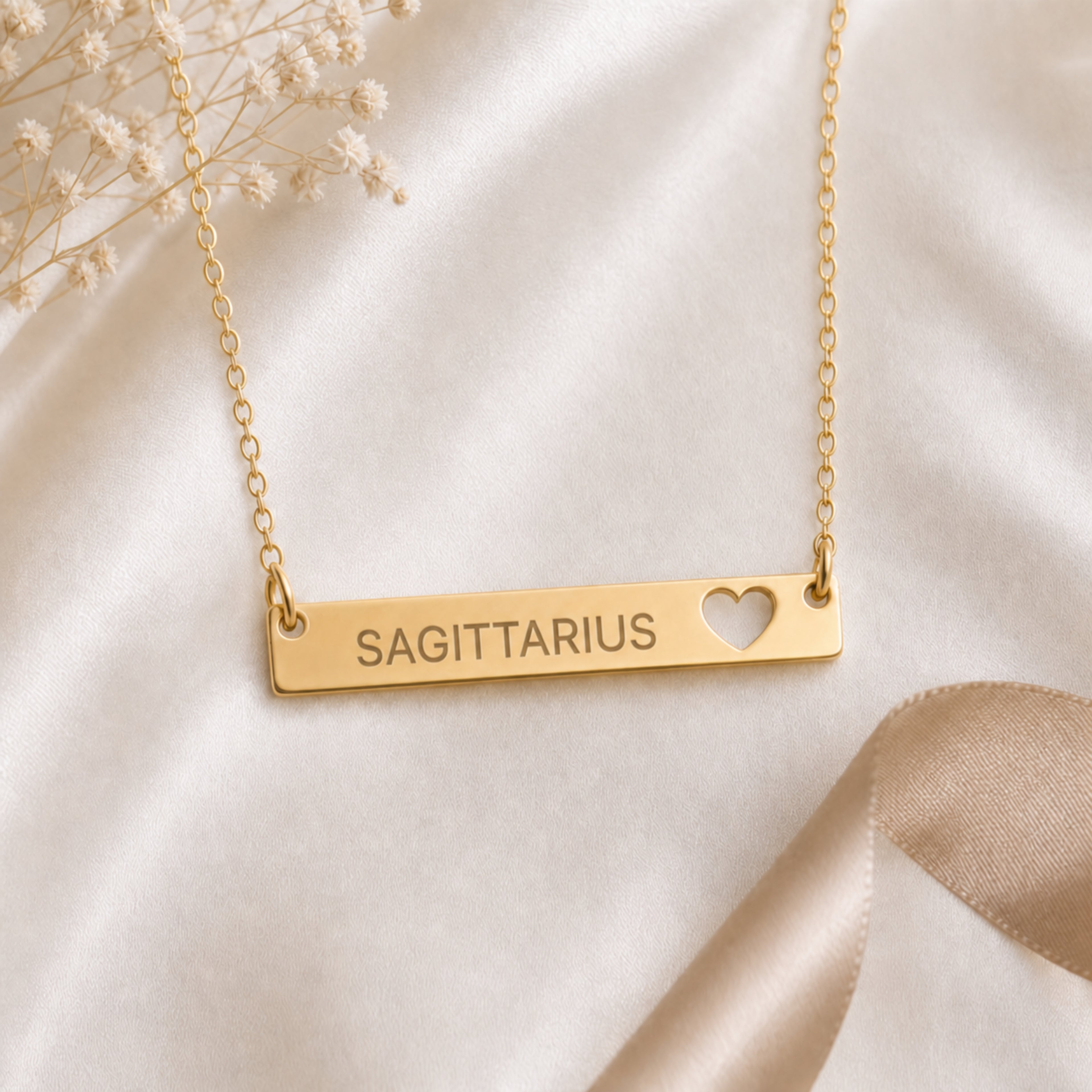 Cream-linen flat lay of the Sagittarius zodiac necklace — 18K Gold cutout heart bar pendant with grey laser-etched SAGITTARIUS, dried baby's breath, editorial styling