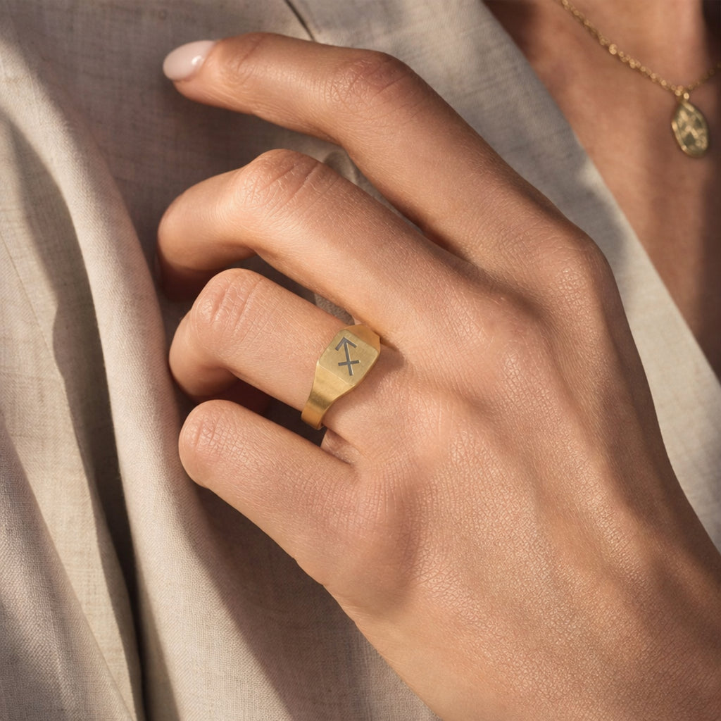Sagittarius zodiac square signet ring on finger — model wearing engraved Sagittarius signet, cream linen lifestyle moment