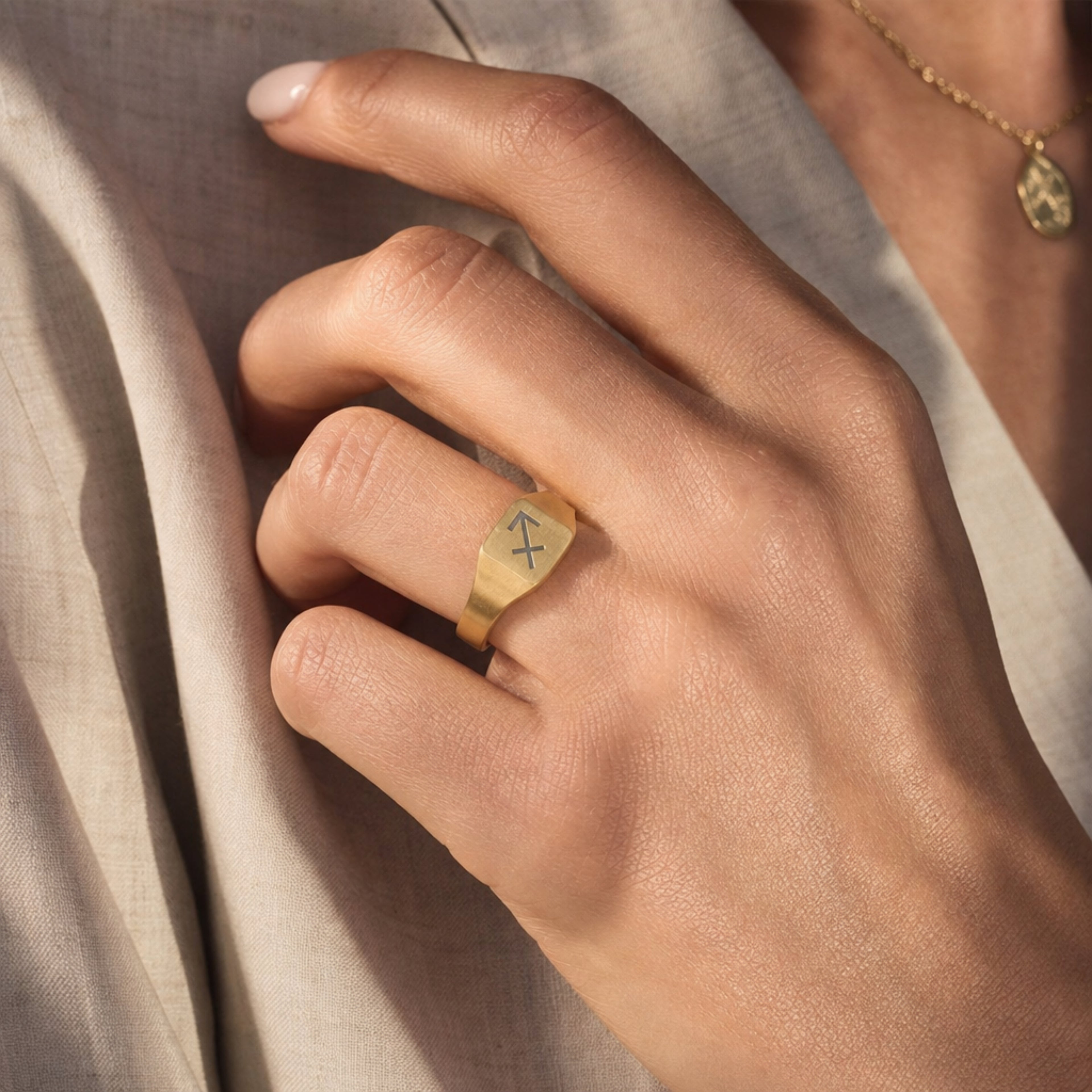 Sagittarius zodiac square signet ring on finger — model wearing engraved Sagittarius signet, cream linen lifestyle moment