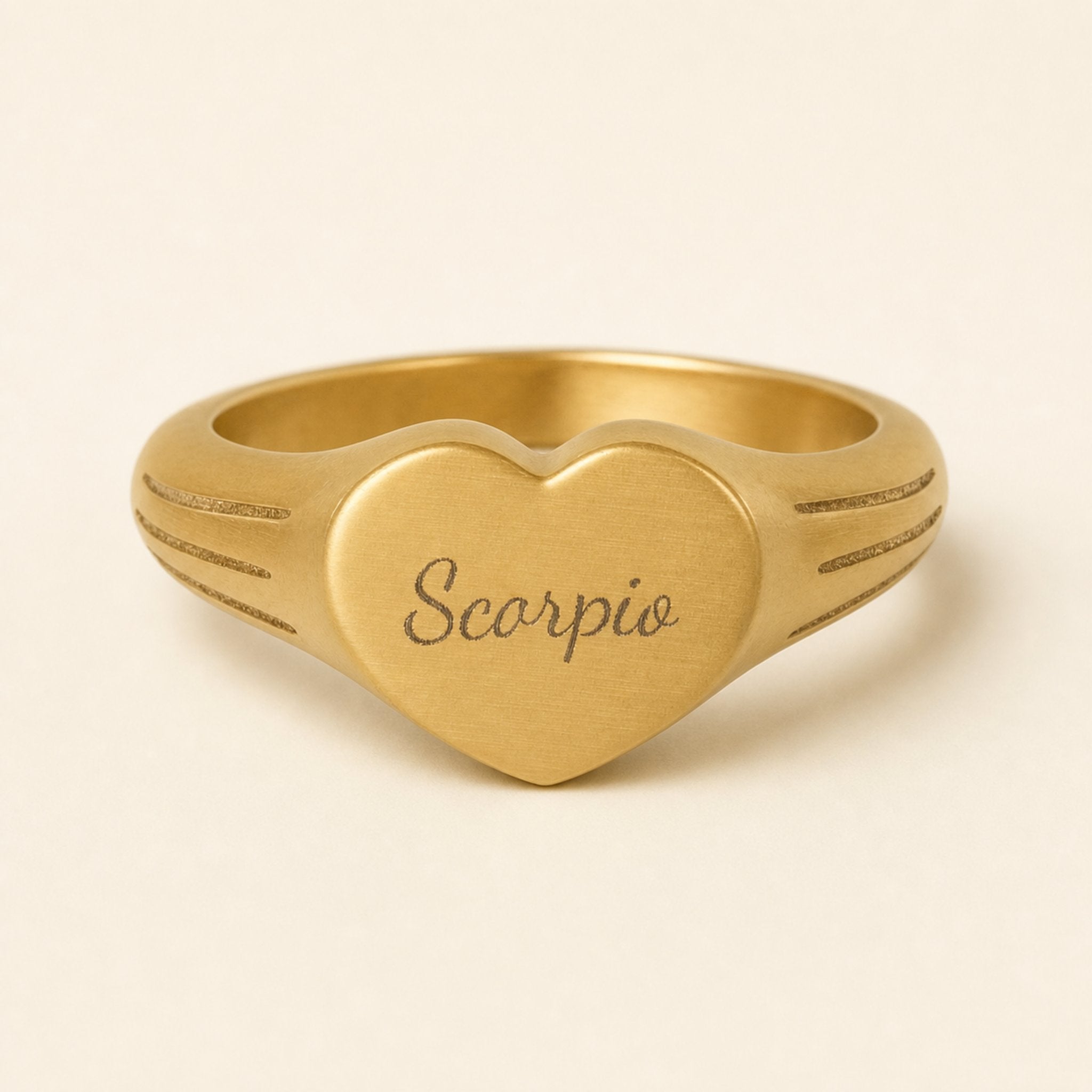 Scorpio zodiac heart signet ring studio front — clean cream backdrop product shot, 18K gold matte PVD